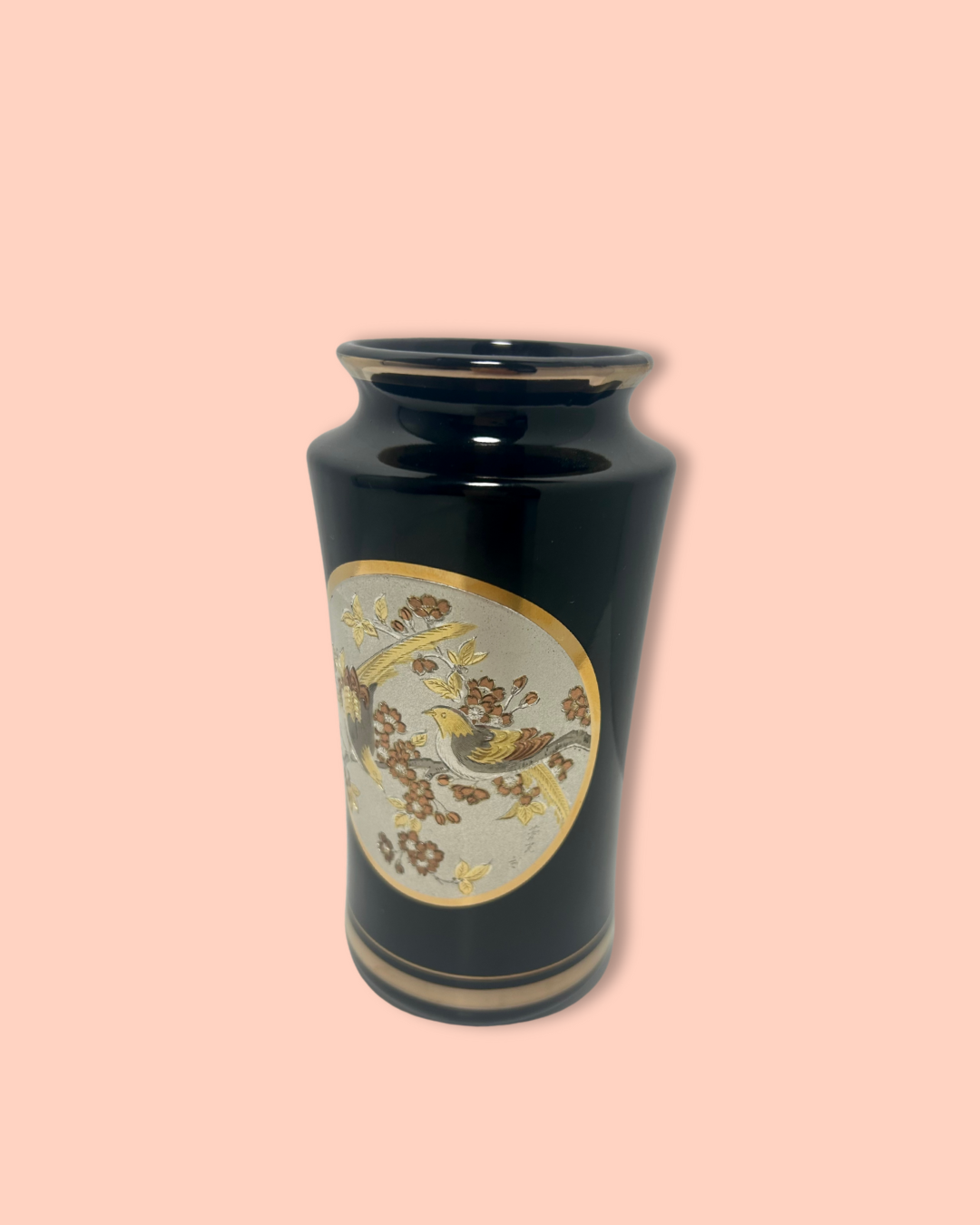 Black vase with decorative circular emblem on a beige background