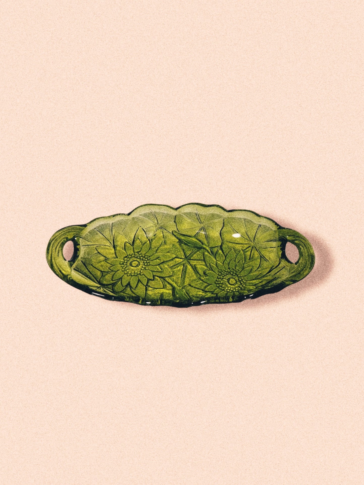 Avocado green glass candy dish with a sunflower pattern on a pink background.