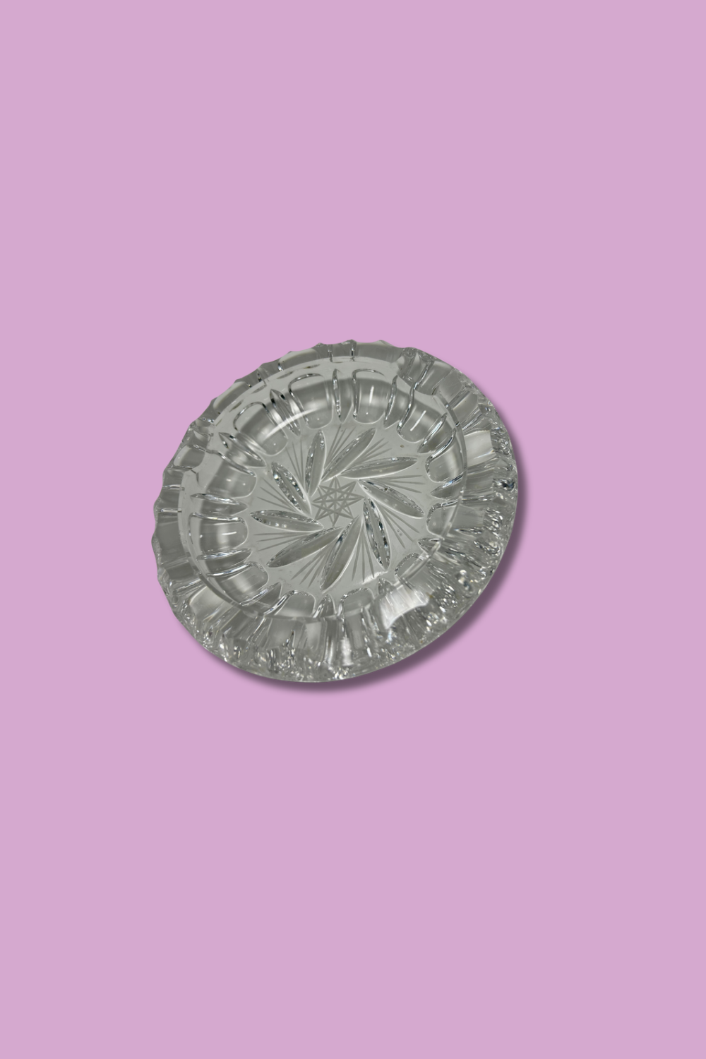 Clear crystal ashtray with Hob Star and pinwheel pattern on a lavender background