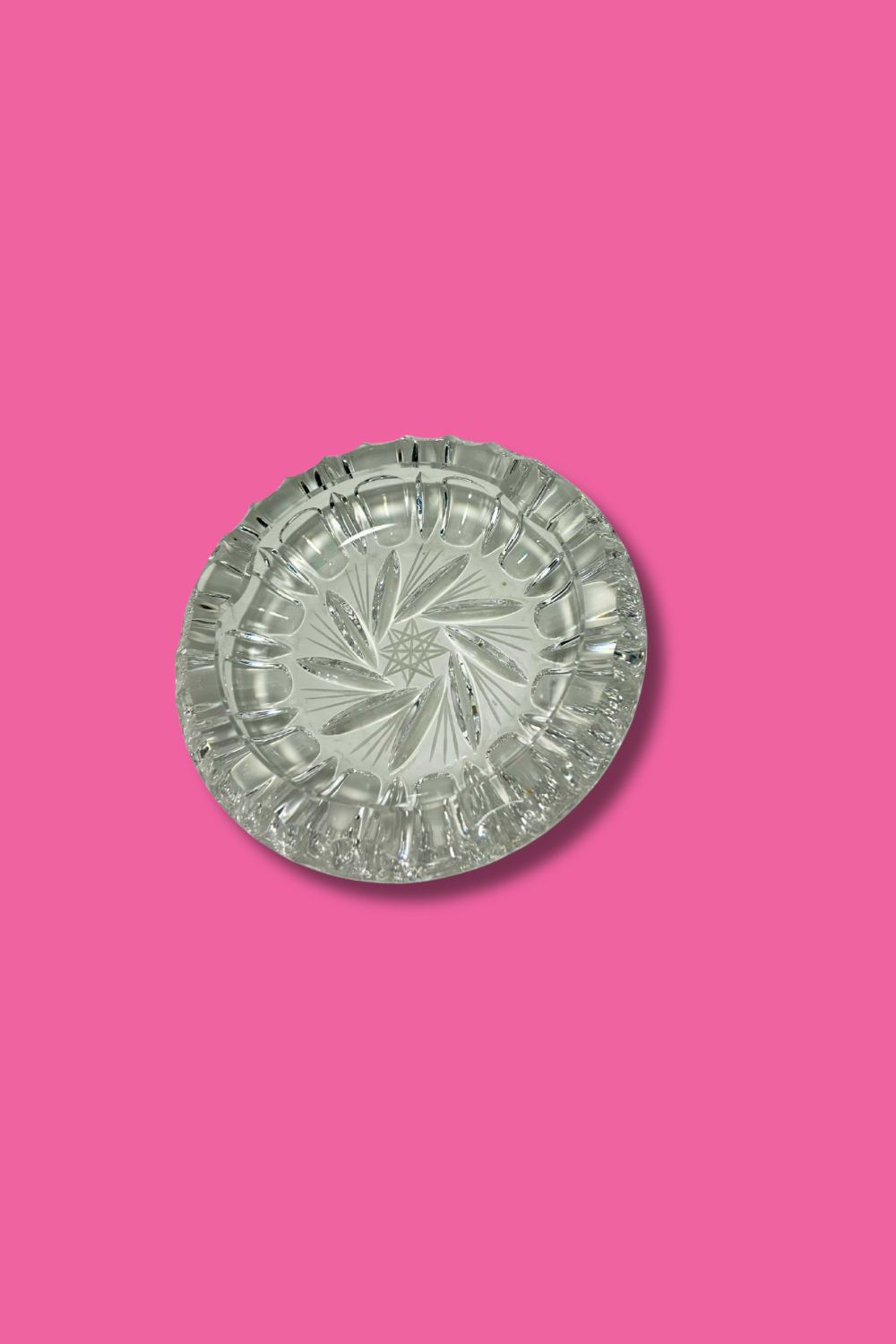 Clear crystal ashtray with Hob Star and pinwheel pattern on a pink background
