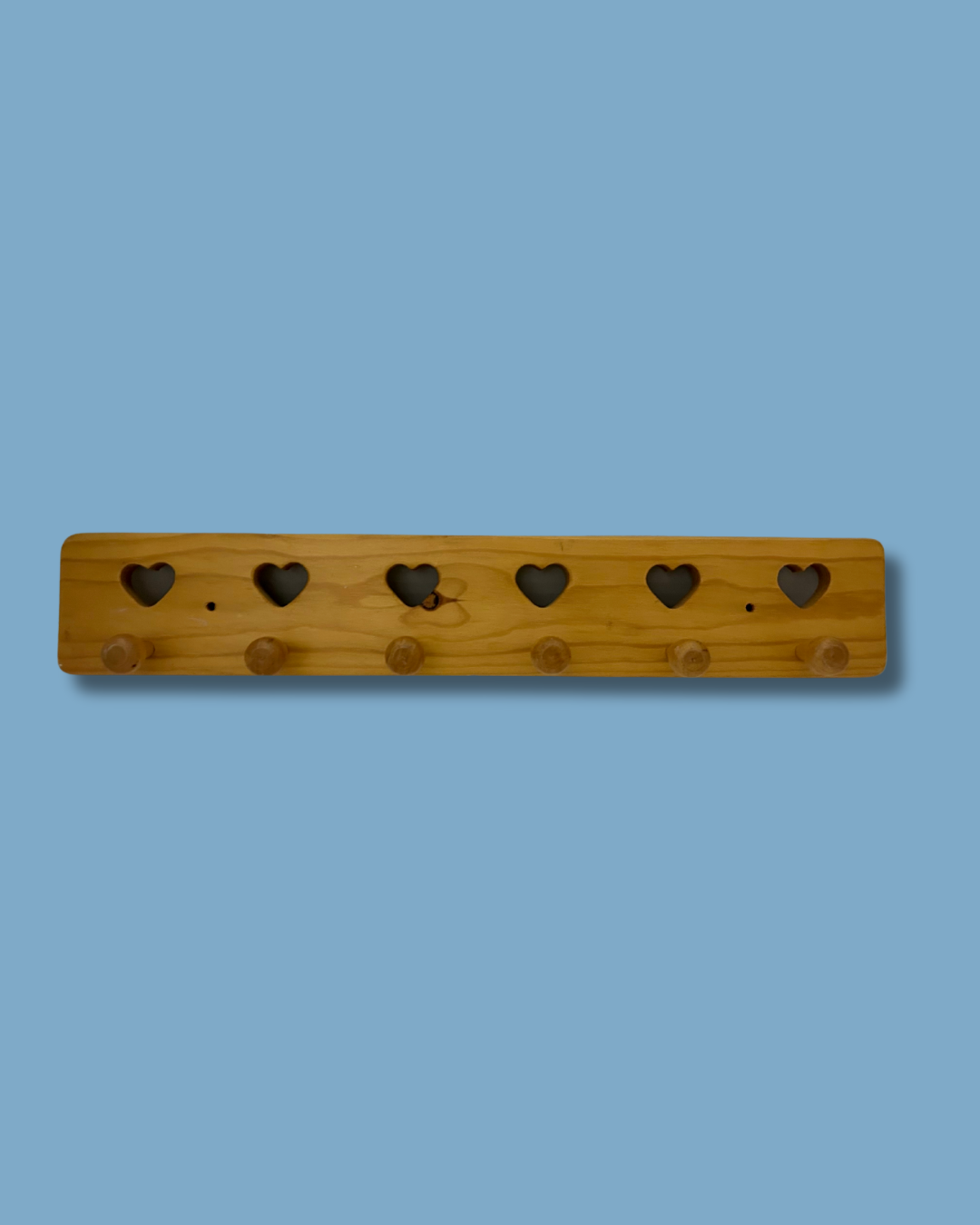 Wooden pegboard with heart-shaped holes on a blue background