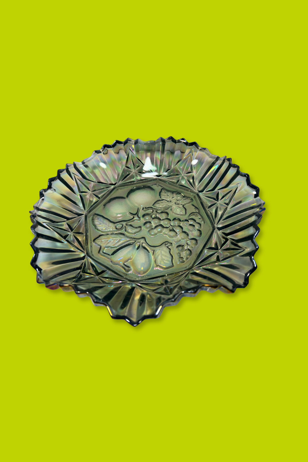 Decorative glass bowl with fish design on a green background