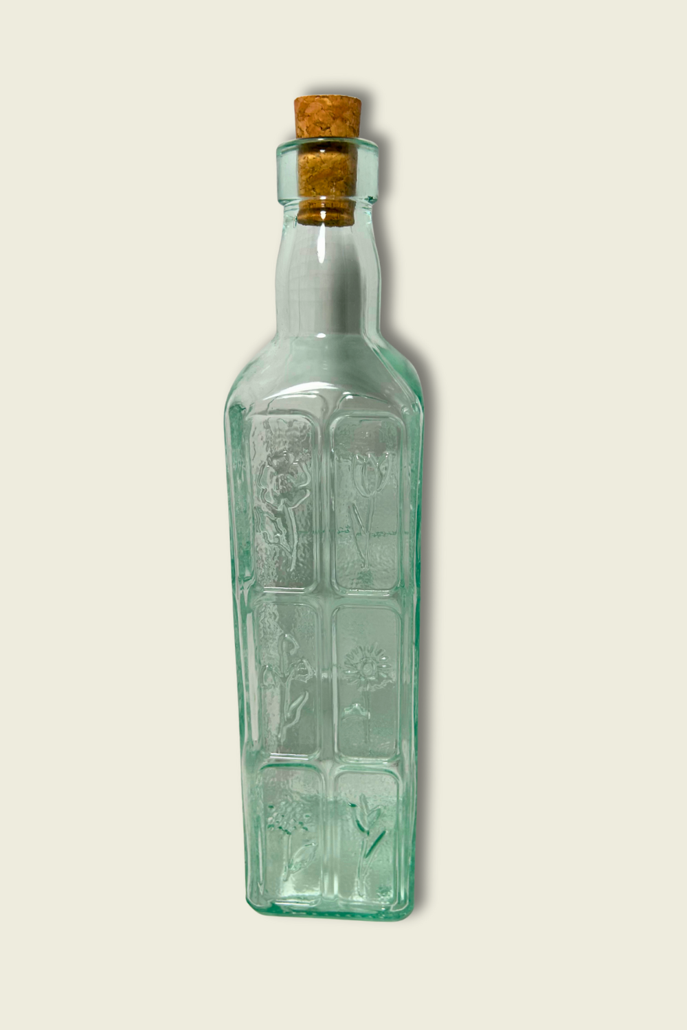 Green glass bottle with cork on a light beige background