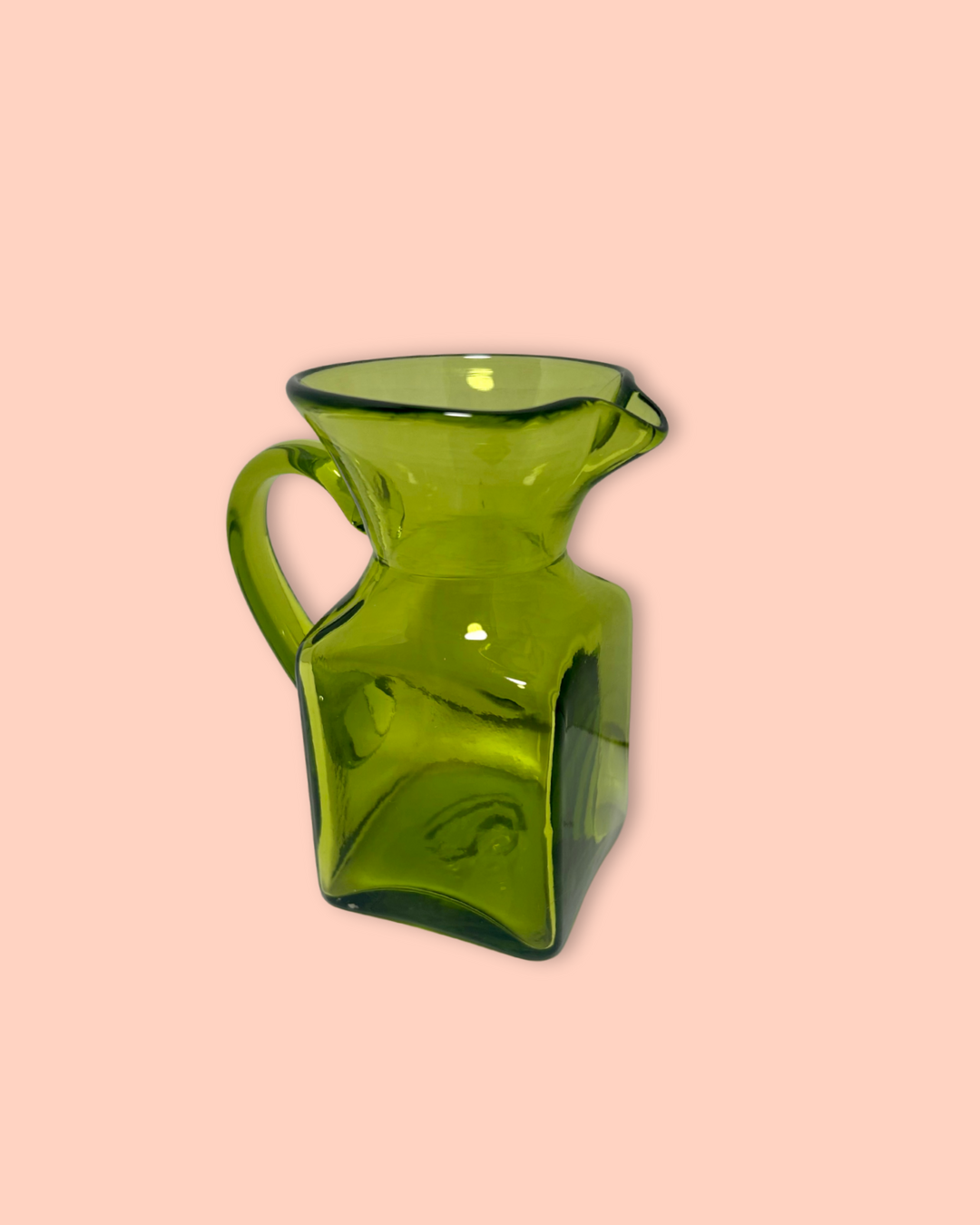 Green glass pitcher on a pink background