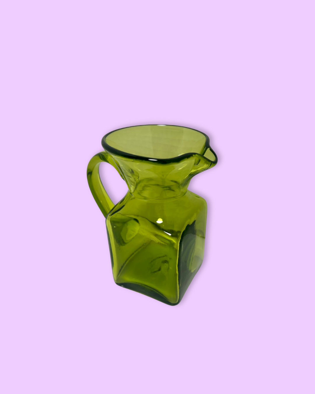 Green glass pitcher on a pink background
