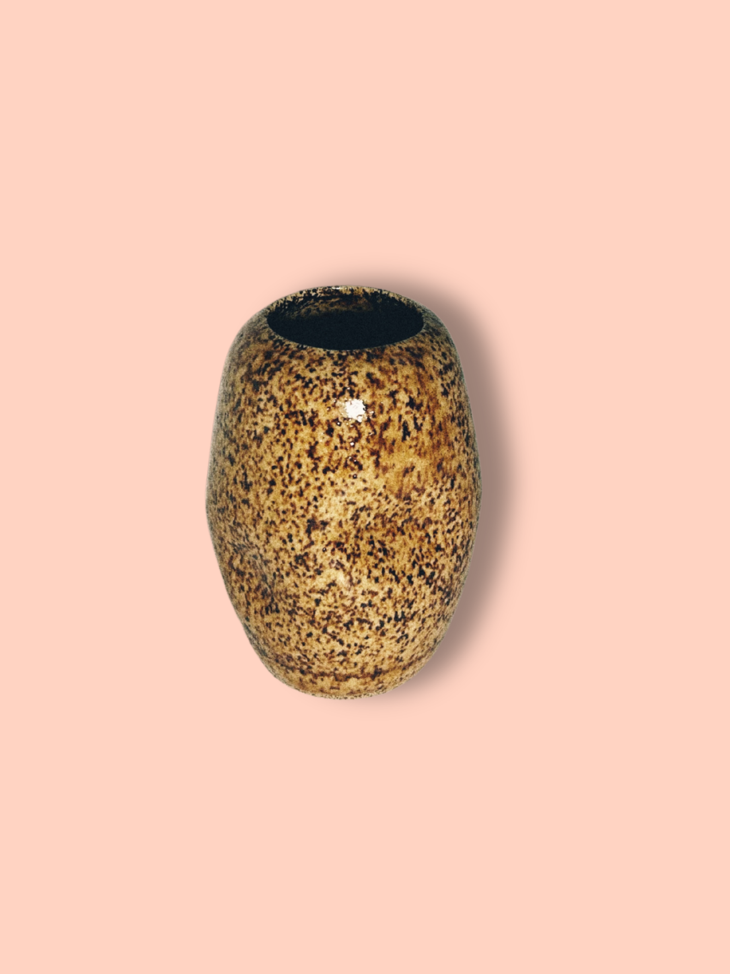 A handmade ceramic brown speckled jar on a pink background.