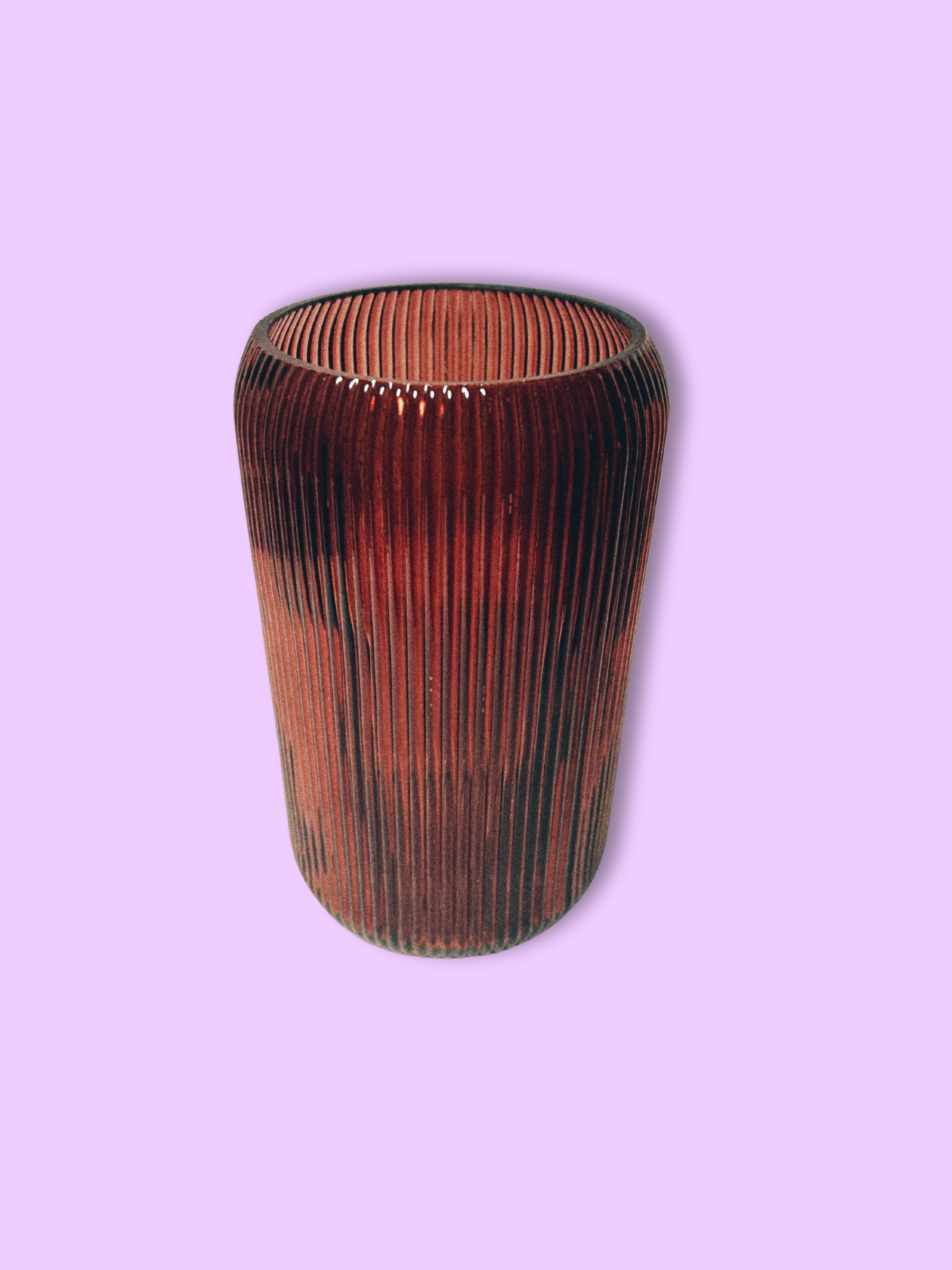 A cylindrical maroon glass vase with vertical ridges against a purple background