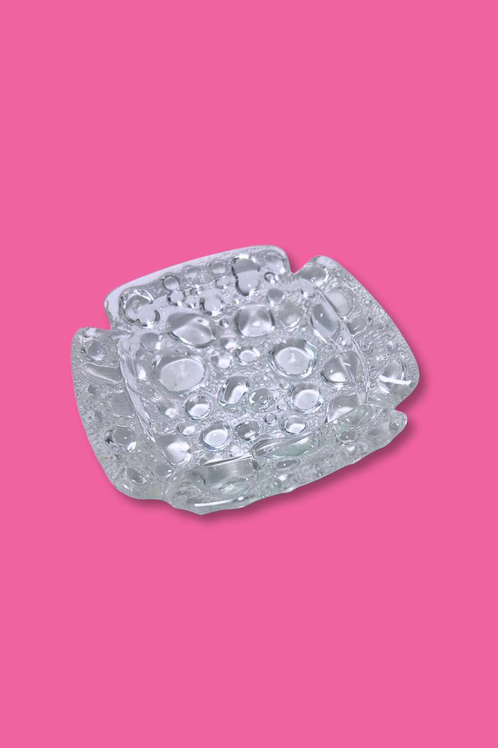 Clear glass candy dish on a pink background