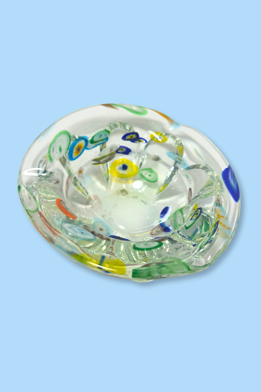 Decorative glass object with colorful patterns on a light blue background