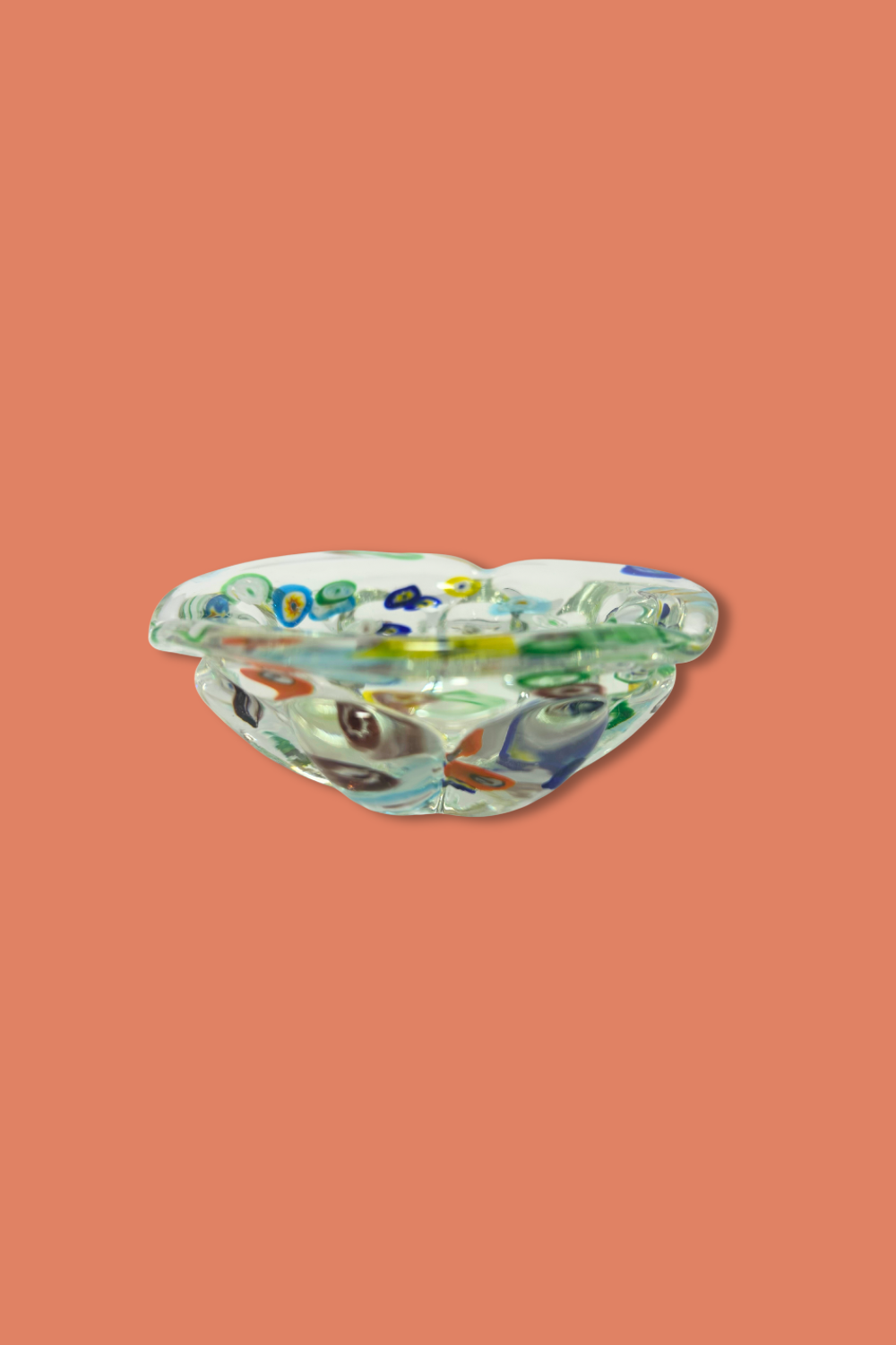 Decorative glass dish with colorful designs on a peach background