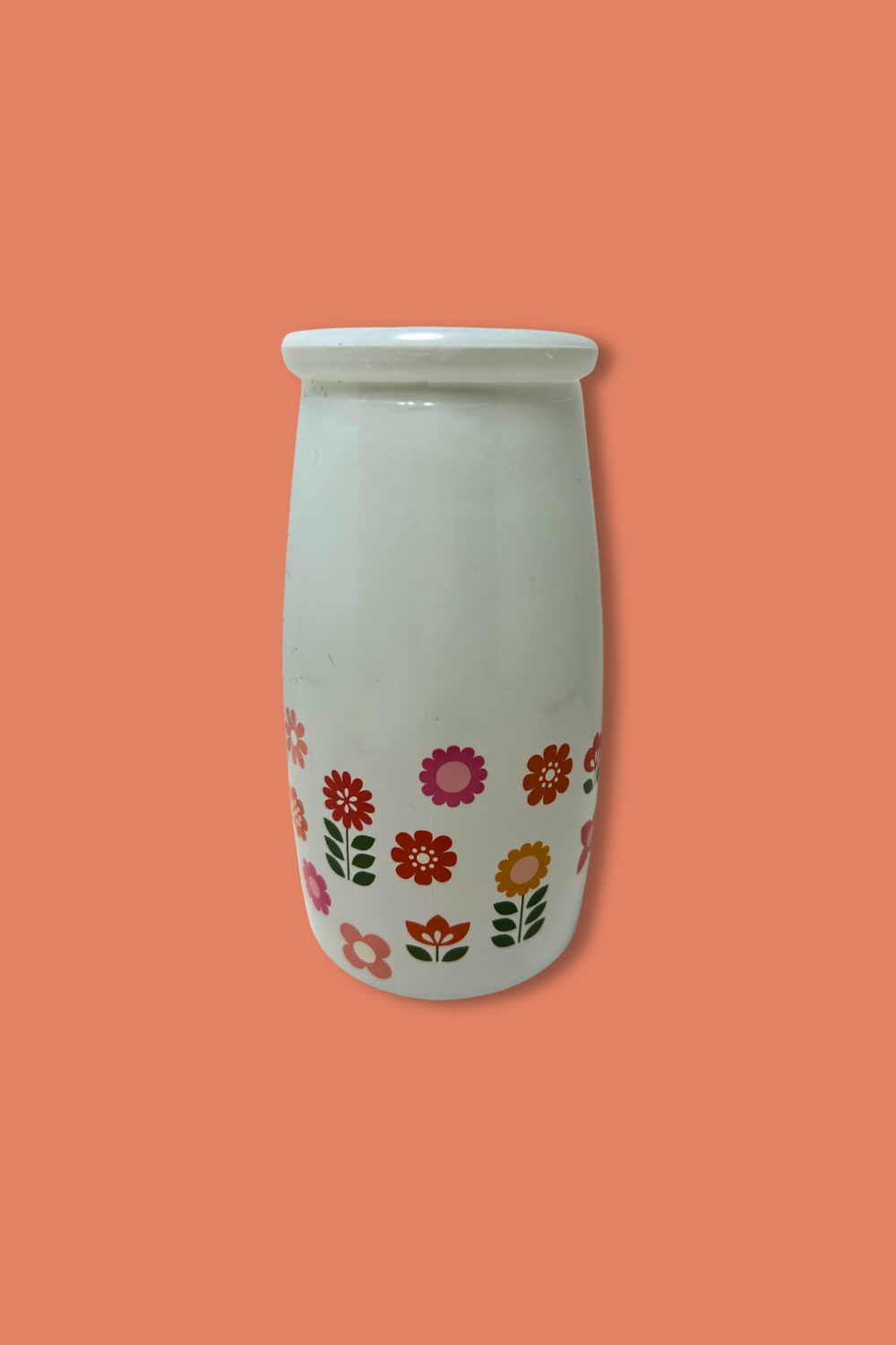 White ceramic vase with floral patterns on a coral background
