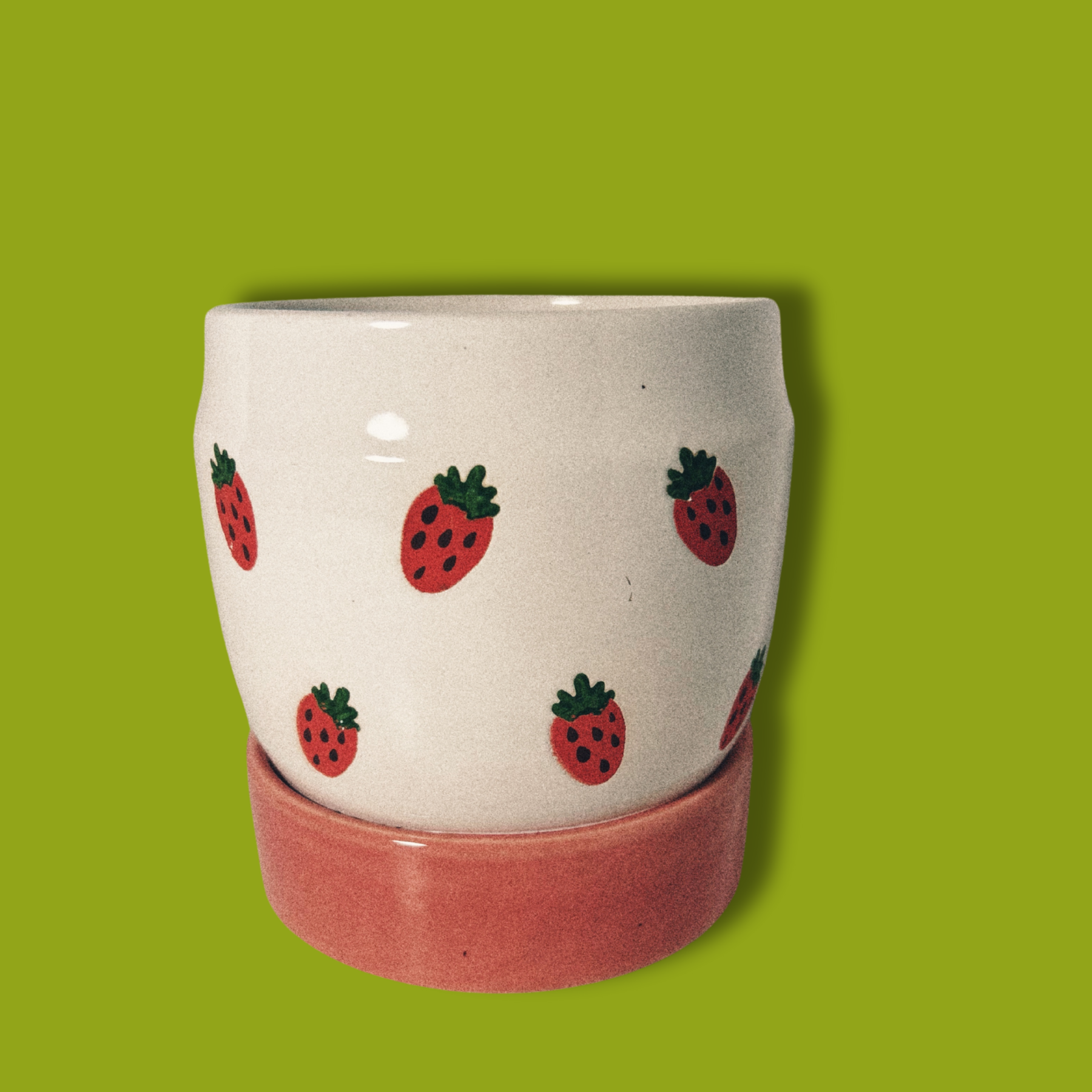 A handpainted ceramic planter with strawberries design on a white background with a pink base.