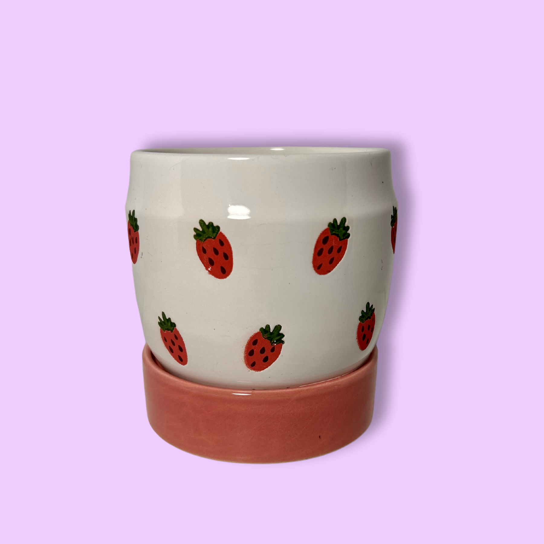 A handpainted ceramic planter with strawberries design on a white background with a pink base.