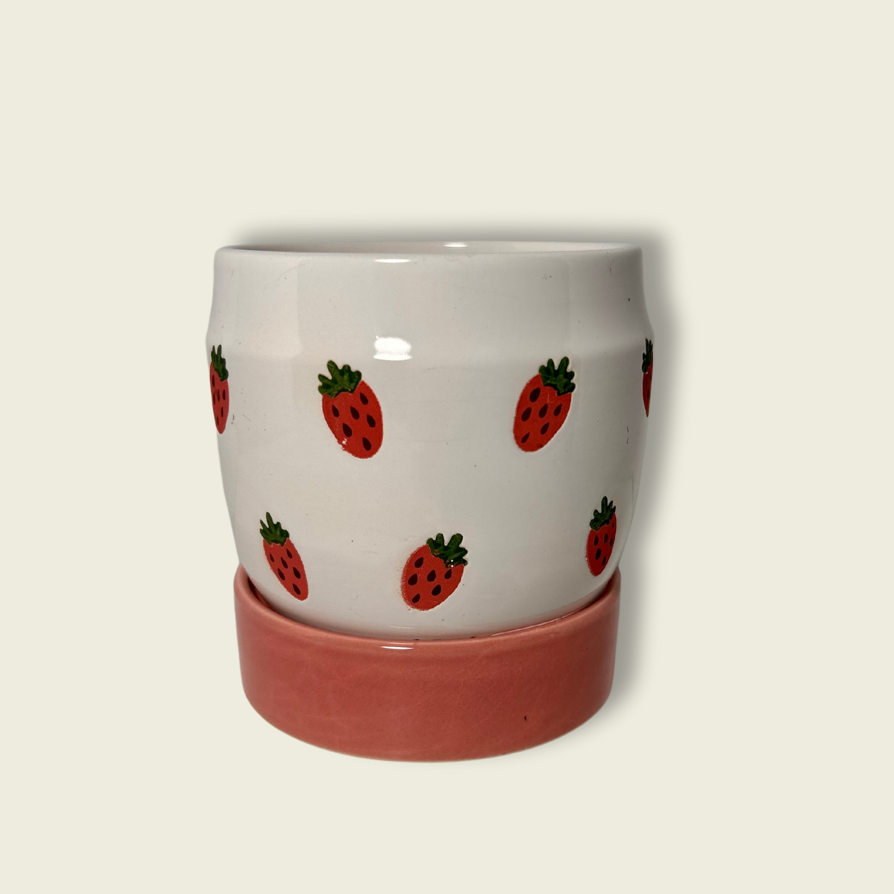 A handpainted ceramic planter with strawberries design on a white background with a pink base.