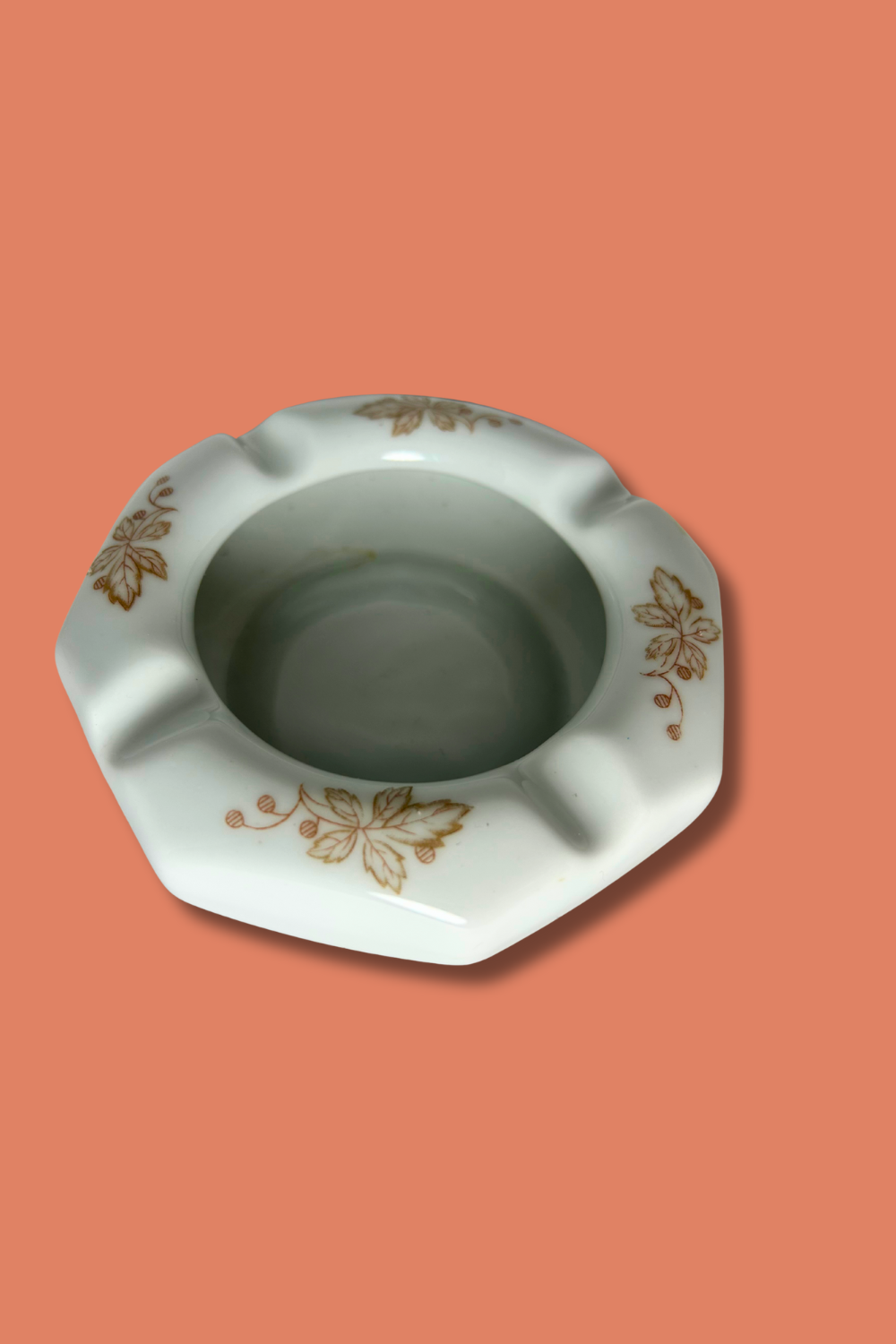 Ceramic ashtray with floral patterns on a peach background