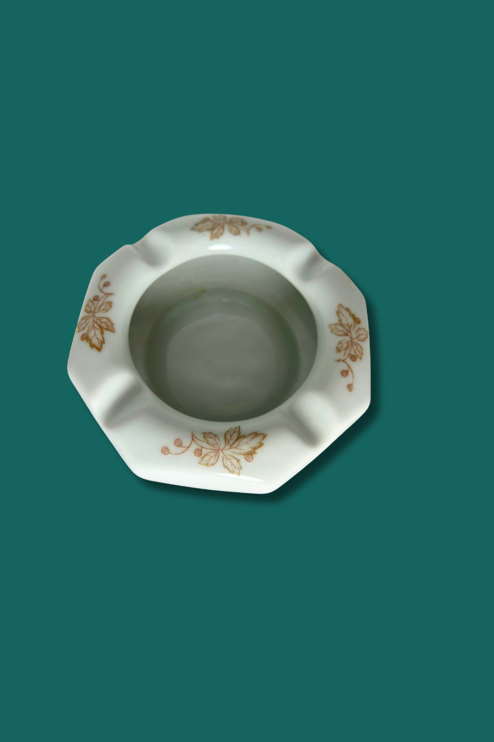 Decorative ceramic ashtray with floral patterns on a teal background
