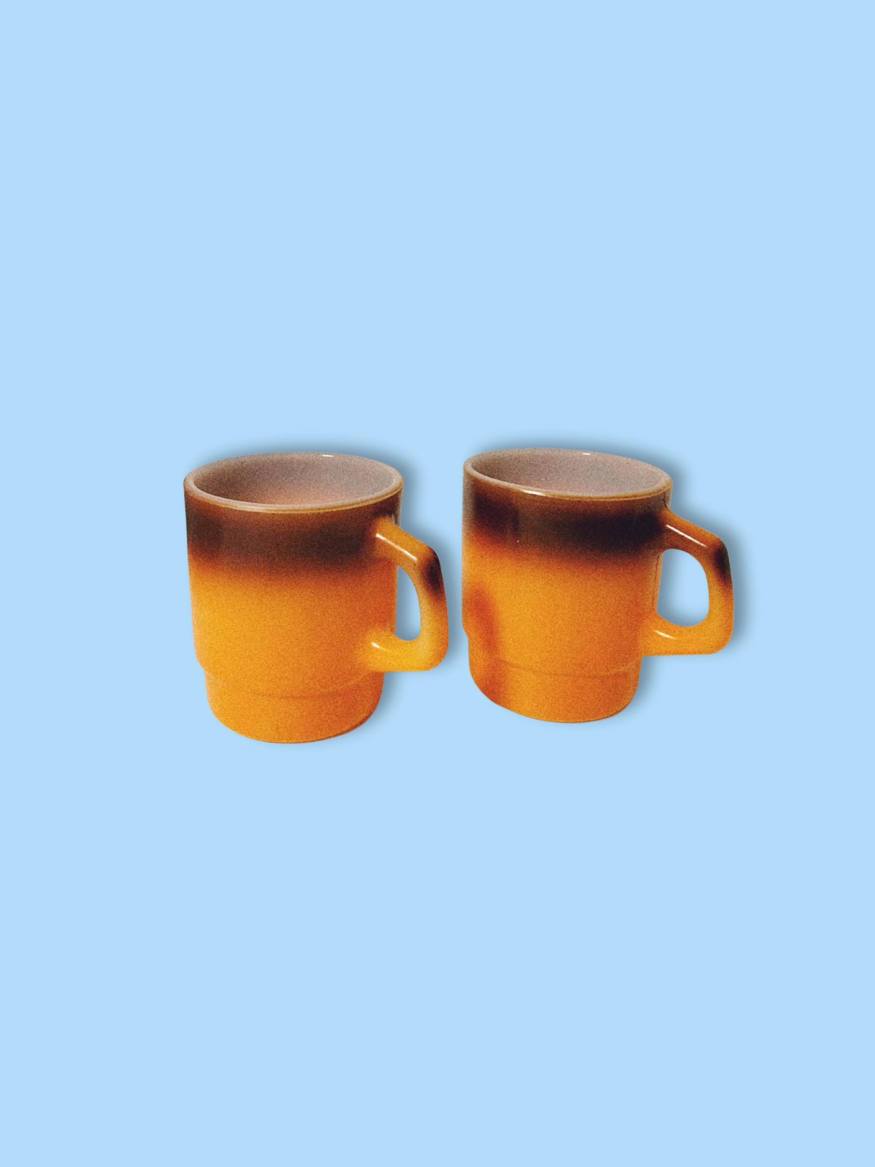 A vintage Anchor Hocking Fire King orange ombre coffee mug against a blue background.