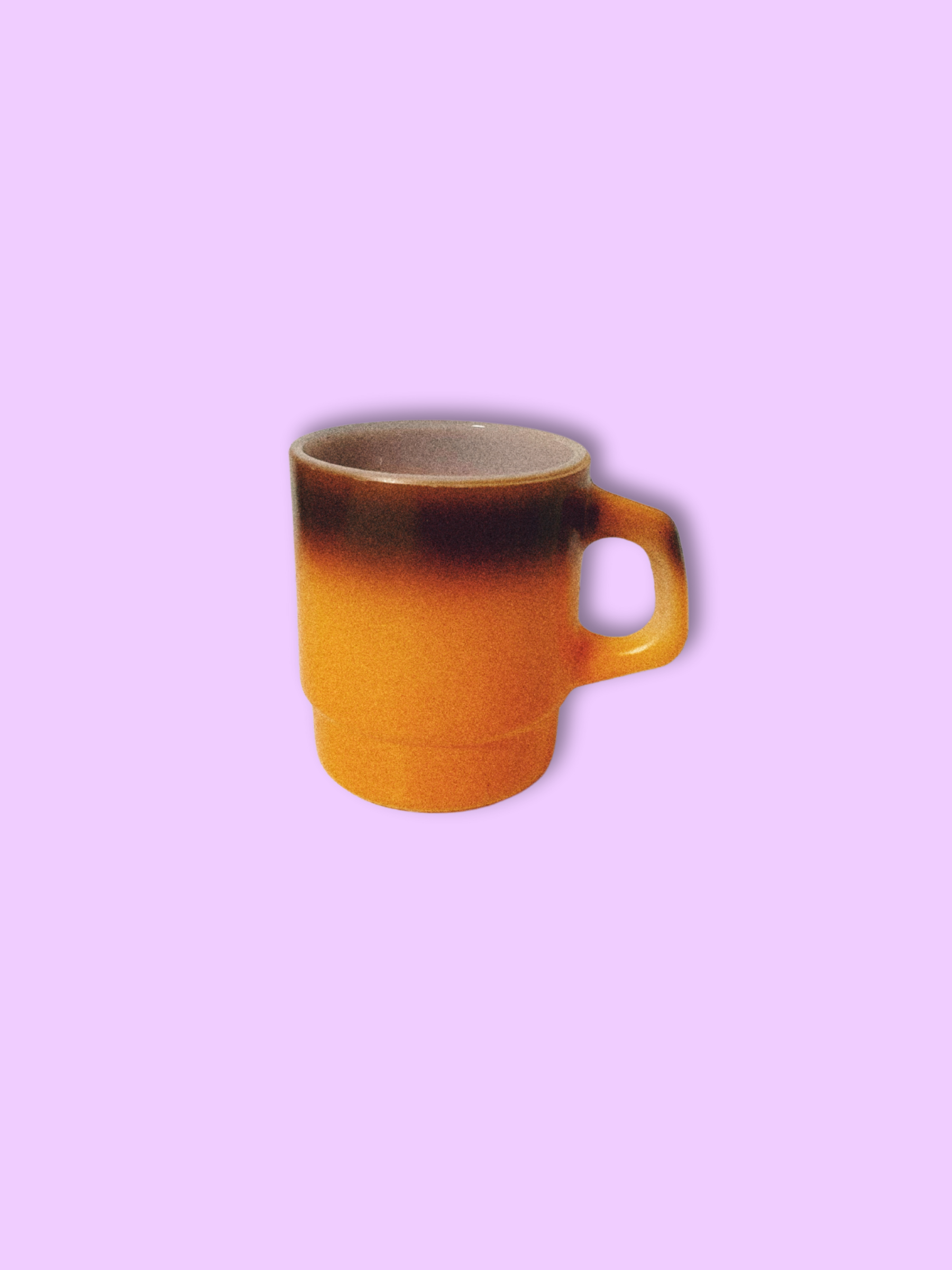 A vintage Anchor Hocking Fire King orange ombre coffee mug against a purple background.