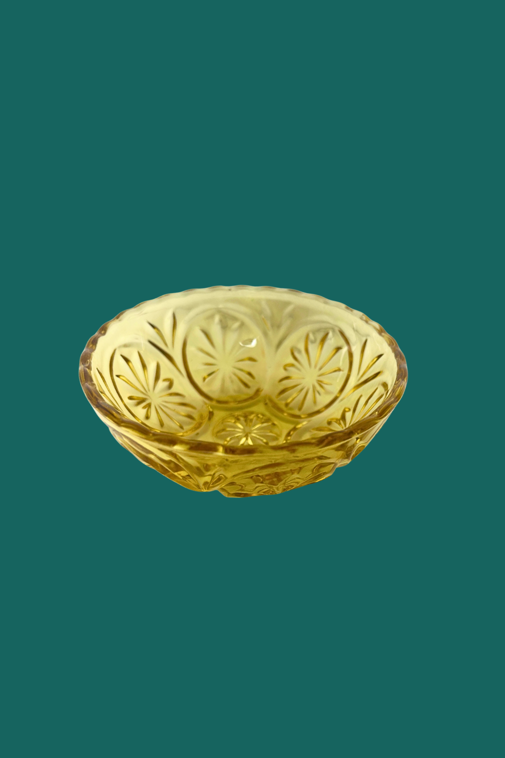 Gold decorative bowl with intricate patterns on a green background