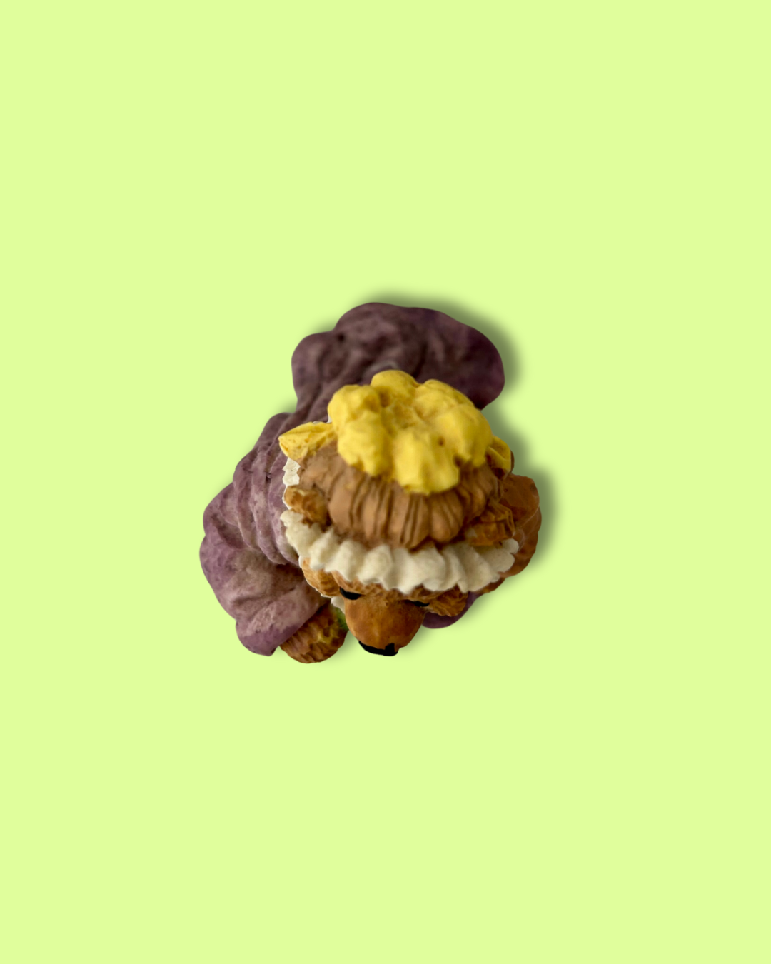 Small figurine of a character with purple hair and yellow headband on a light green background