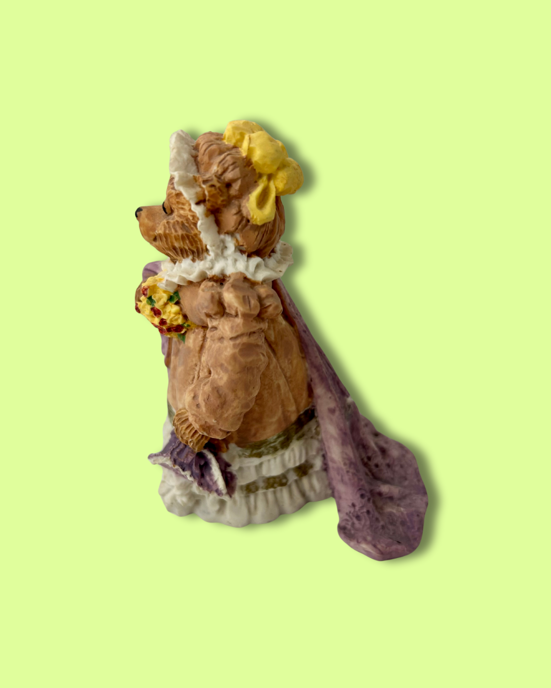 Decorative figurine of a fox in a dress with a yellow bow on a light green background
