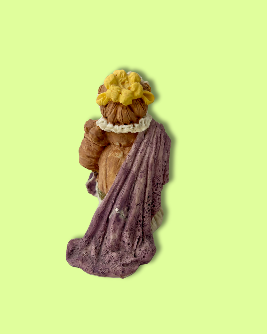 Figurine of a woman with a yellow flower in her hair on a light green background