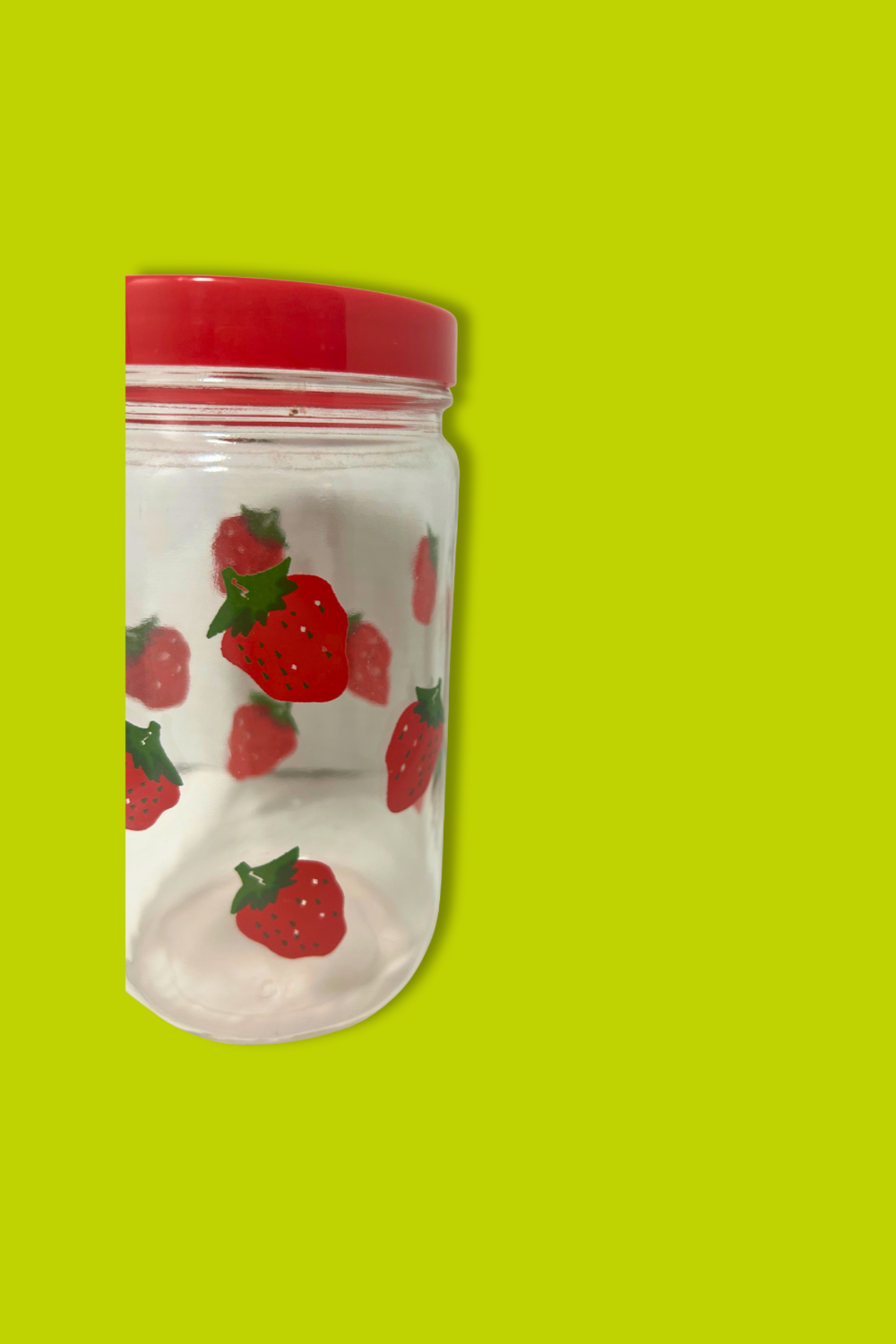 Clear container with red lid and strawberry pattern on a green background