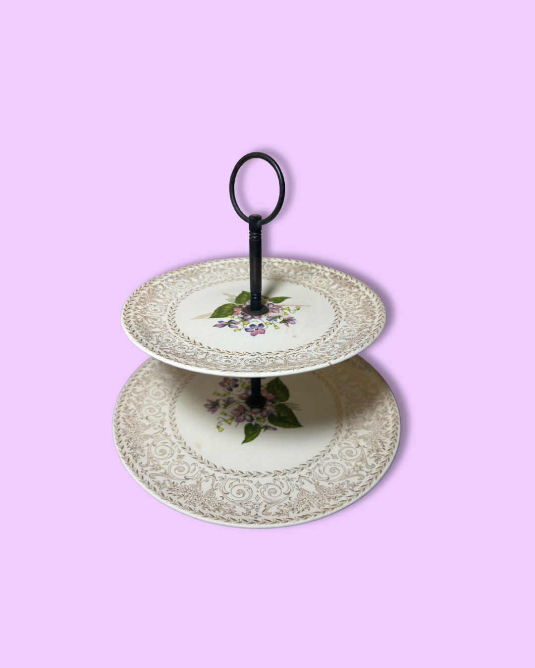 Two-tiered decorative plate stand with floral design on a pink background