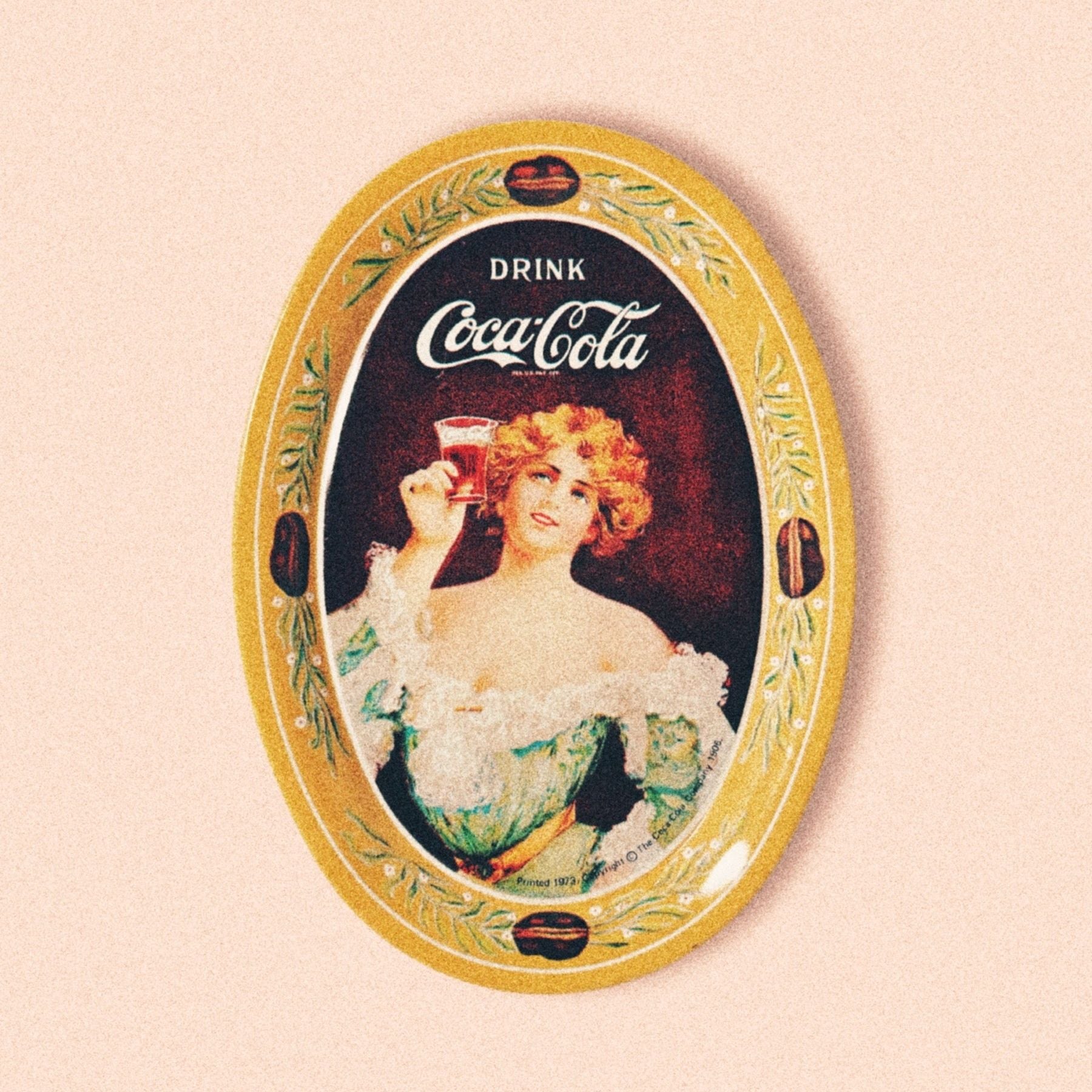 A vintage 1970s oval-shaped Coca Cola collectible plate featuring a 1917 Gibson Style Art design with a woman holding a Coca Cola glass.