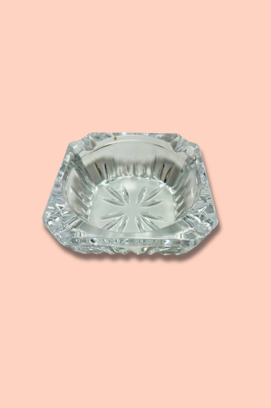 Clear crystal ashtray with starburst pattern on a pink background