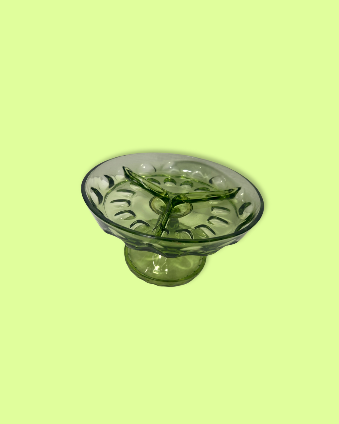 Green glass bowl with decorative design on a light green background