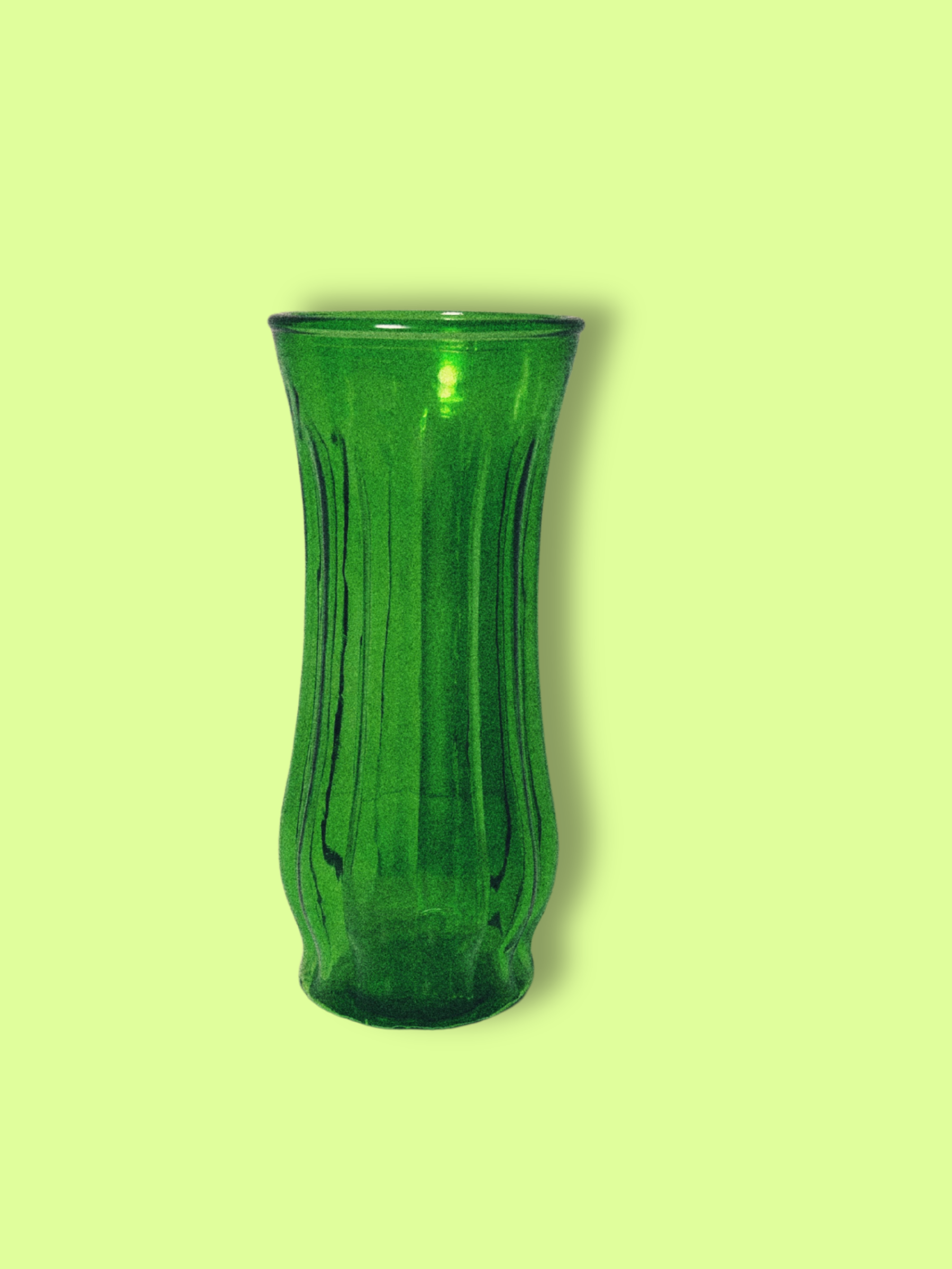 A green glass vase with a ribbed design, displayed against a green background