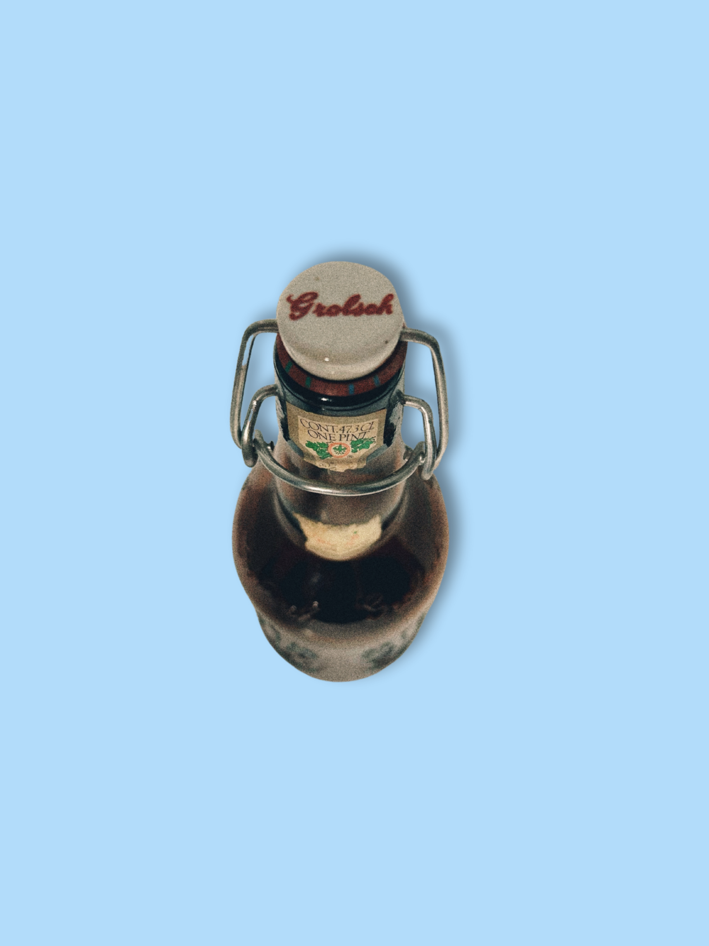 A vintage Grolsch beer bottle with a brown tint and decorative patterns, featuring a white cap and a label that partially shows the brand name.