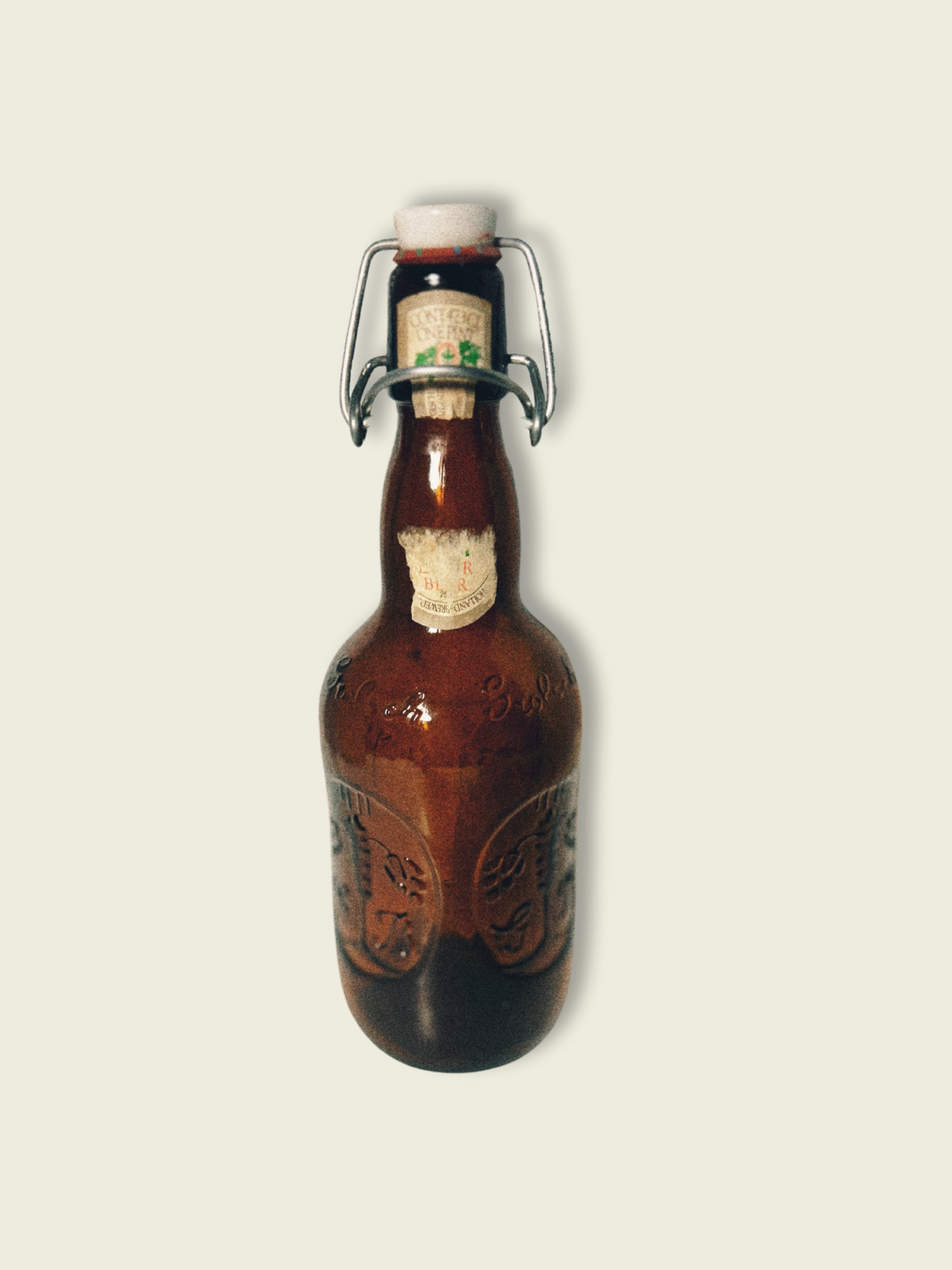 A vintage Grolsch beer bottle with a brown tint and decorative patterns, featuring a white cap and a label that partially shows the brand name.