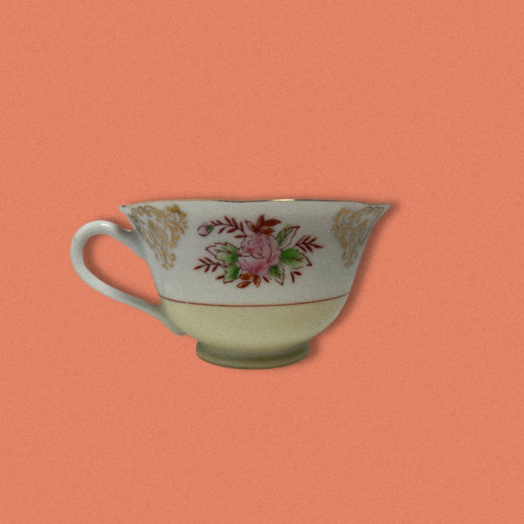 A vintage hand painted Japanese tea cup with floral patterns on a peach background.