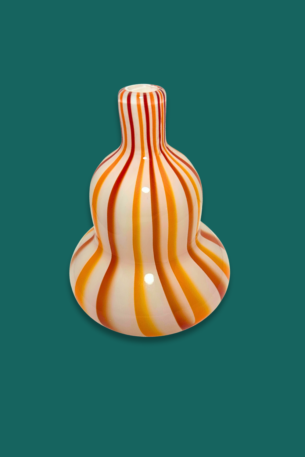 Decorative vase with wavy orange and white pattern on a green background