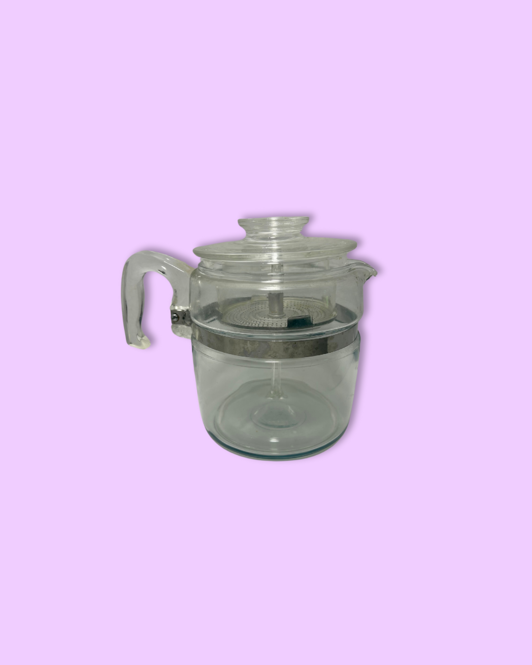 Clear glass teapot with a lid on a pink background
