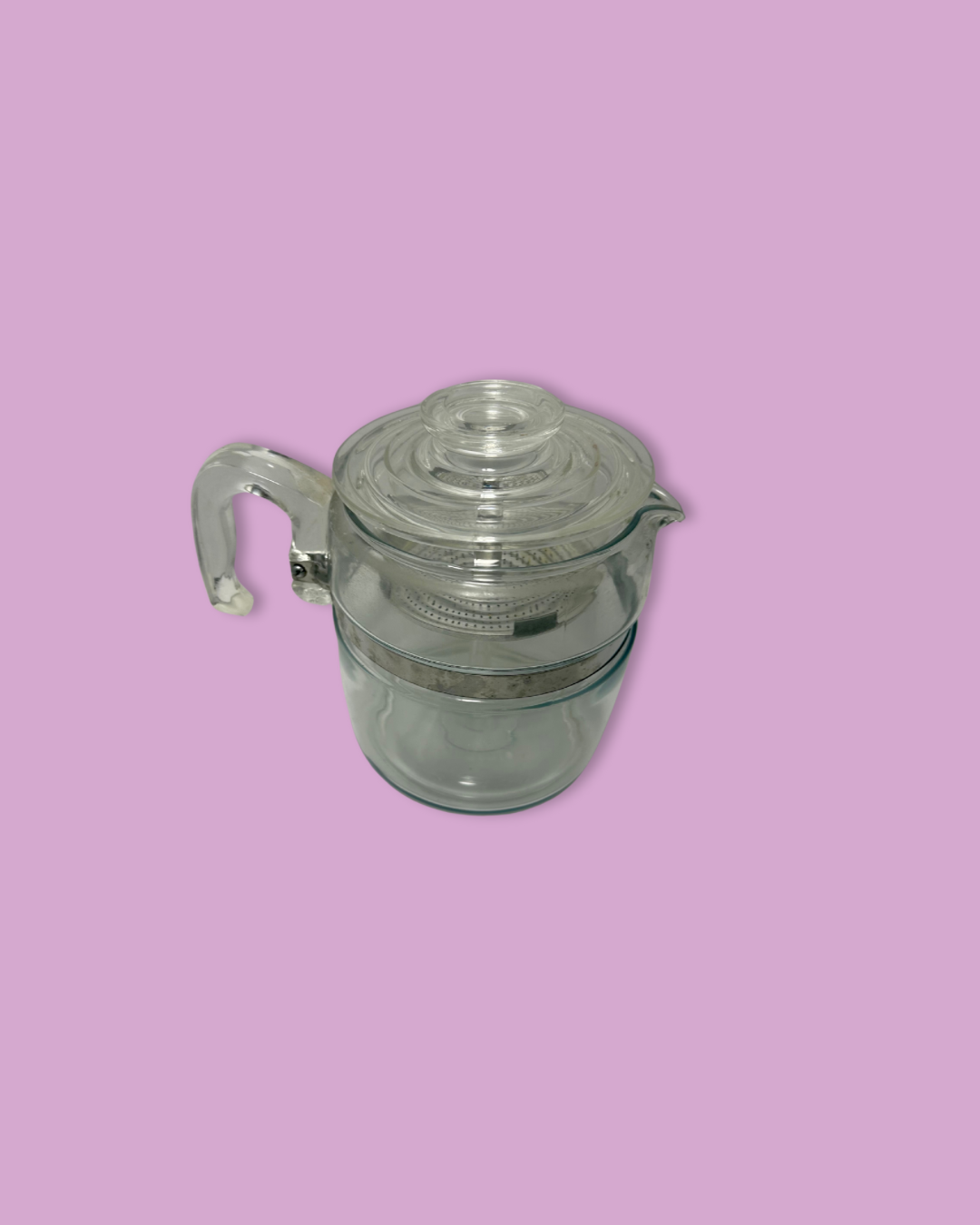 Clear glass pitcher with metal handle on a pink background
