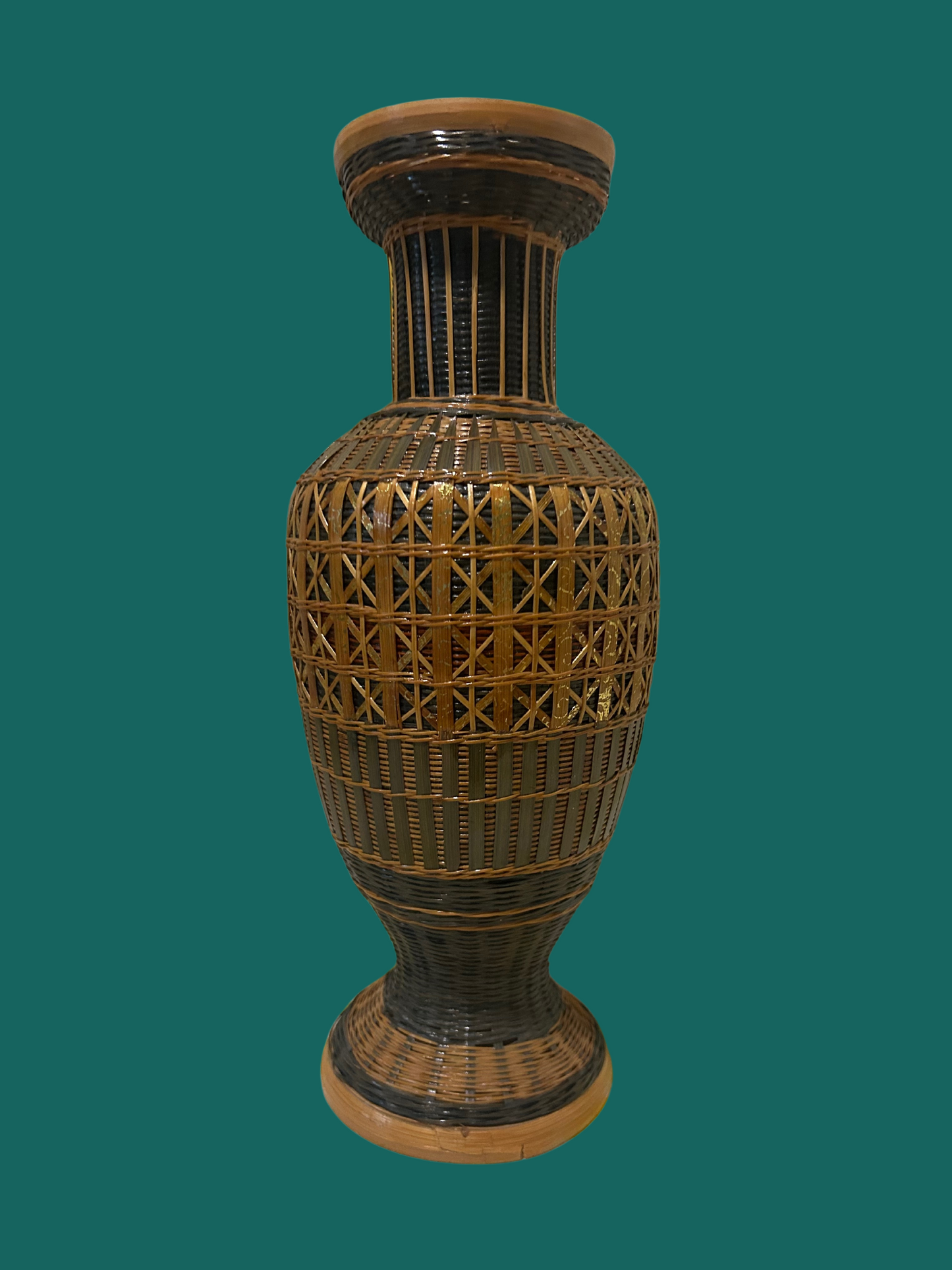 A vintage rattan vase with a geometric pattern, predominantly in shades of brown and beige, against a teal background.