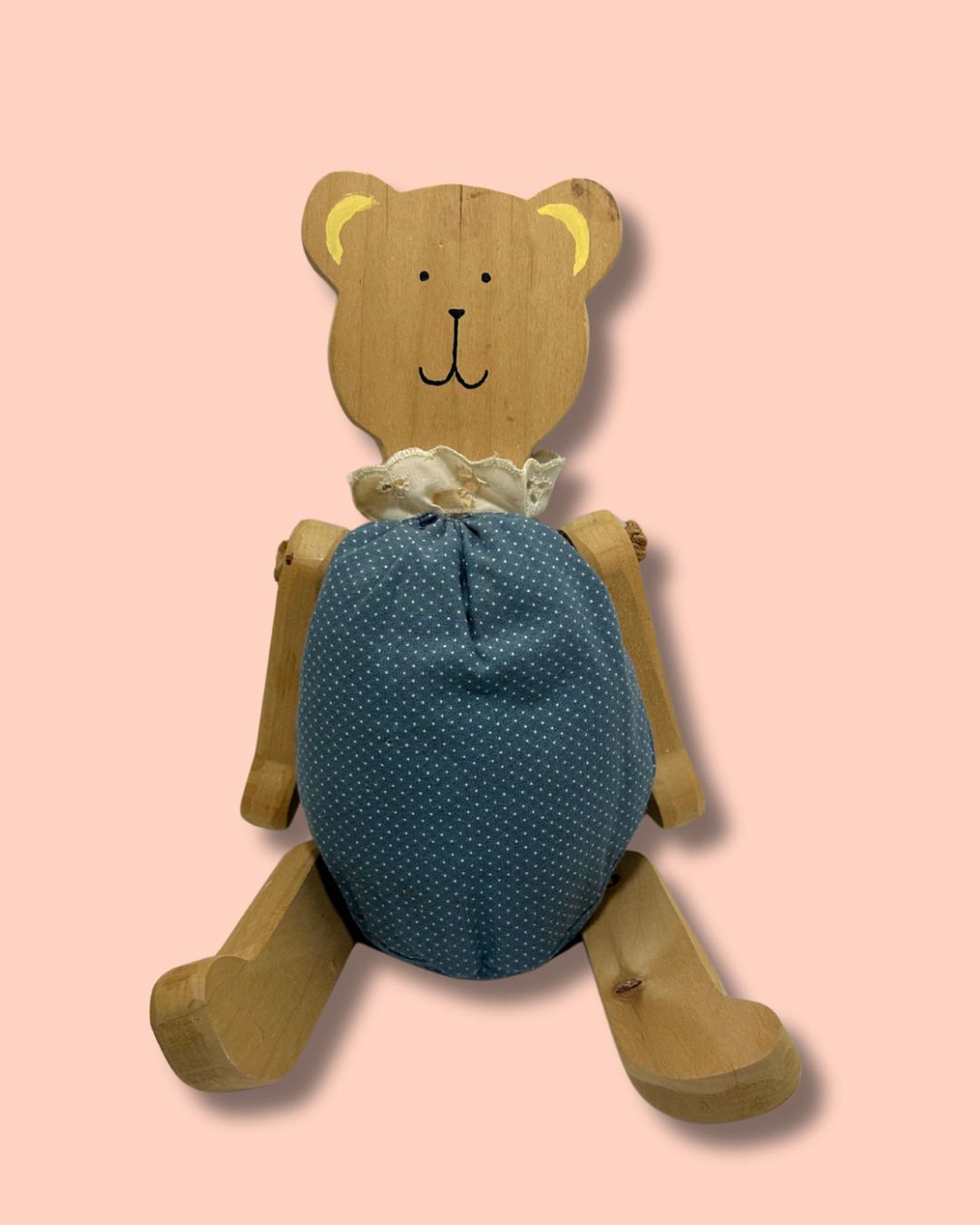 Wooden teddy bear with a blue polka dot body on a pink background