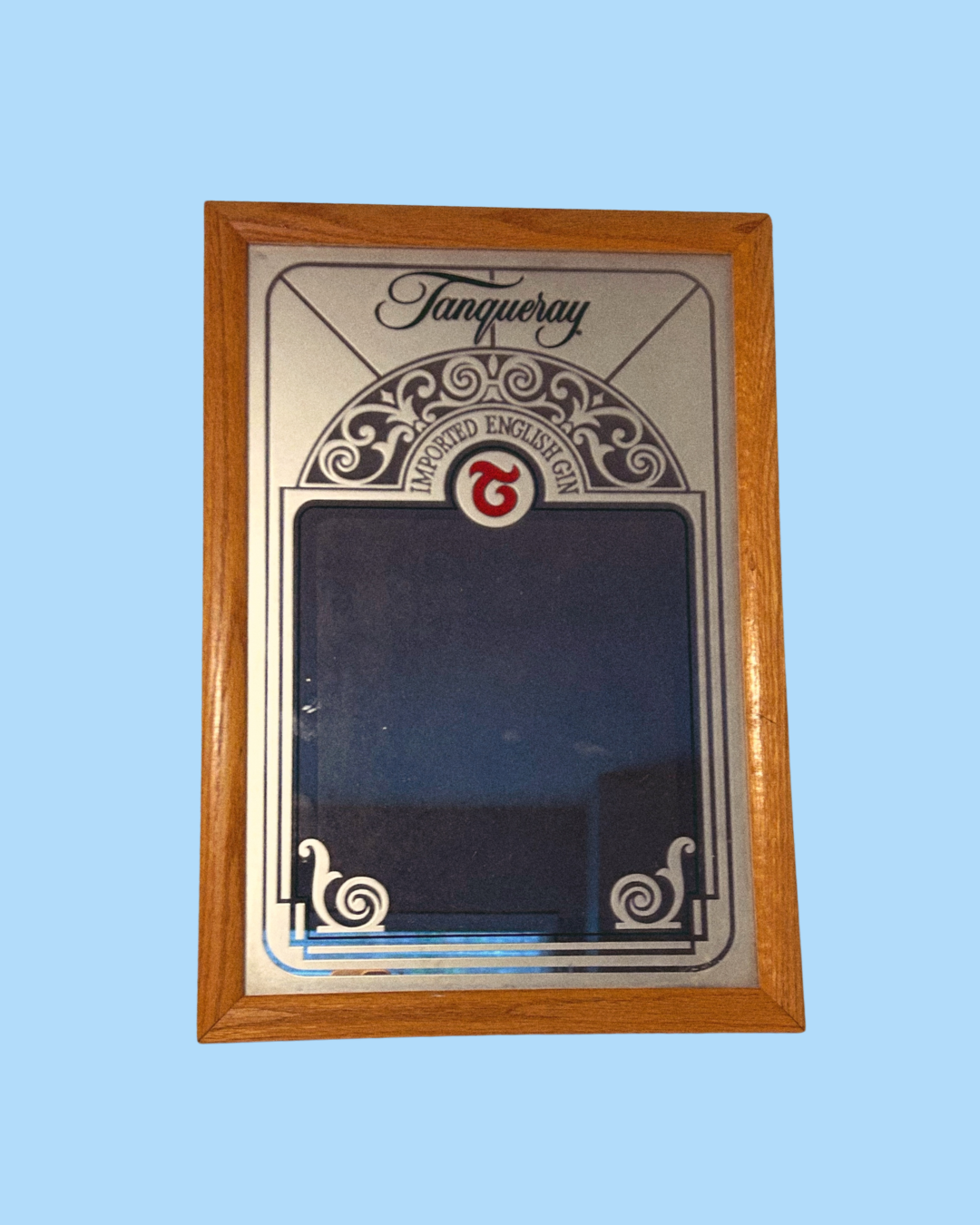 A vintage Tanqueray branded mirror with a decorative wooden frame