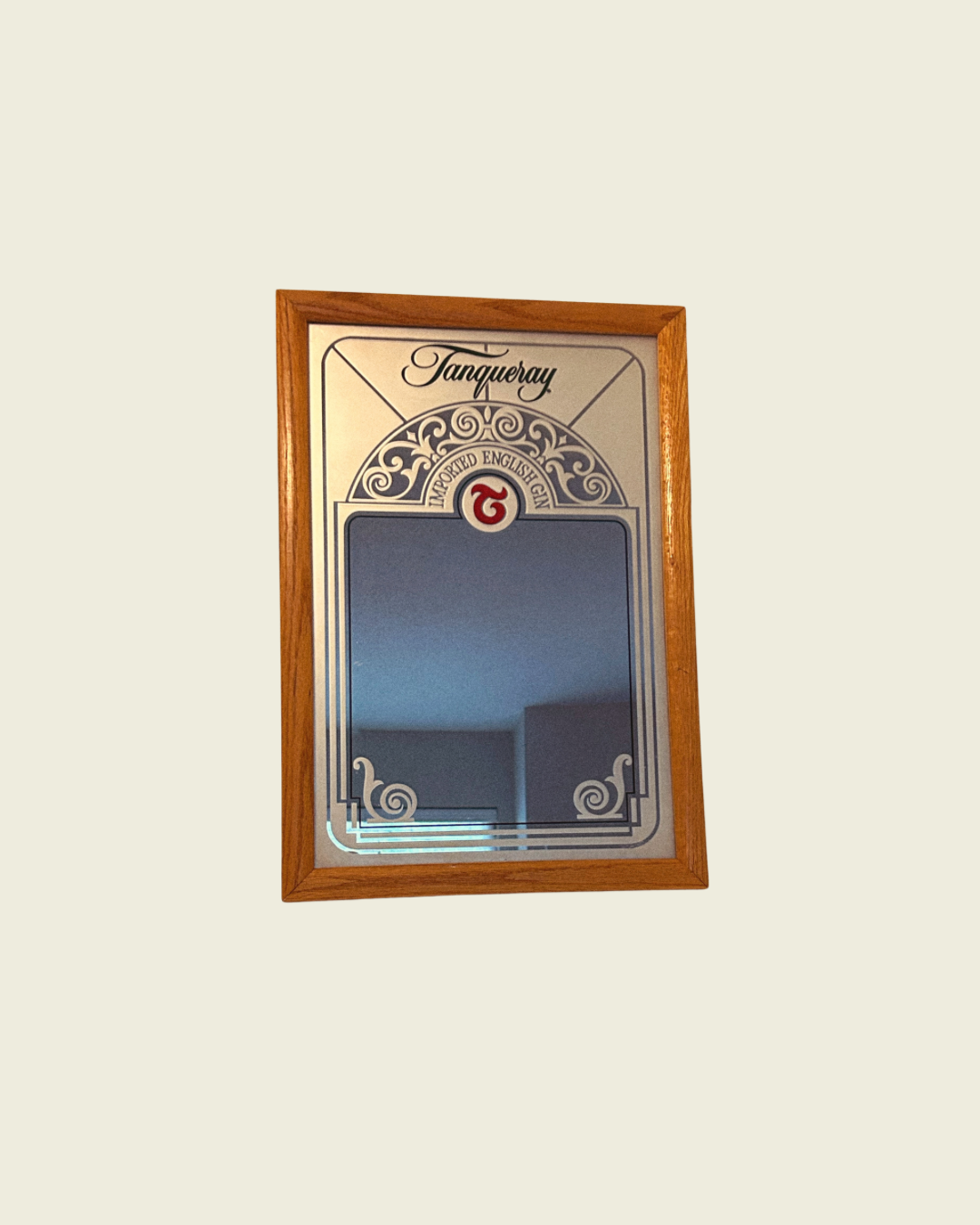 A vintage Tanqueray branded mirror with a decorative wooden frame