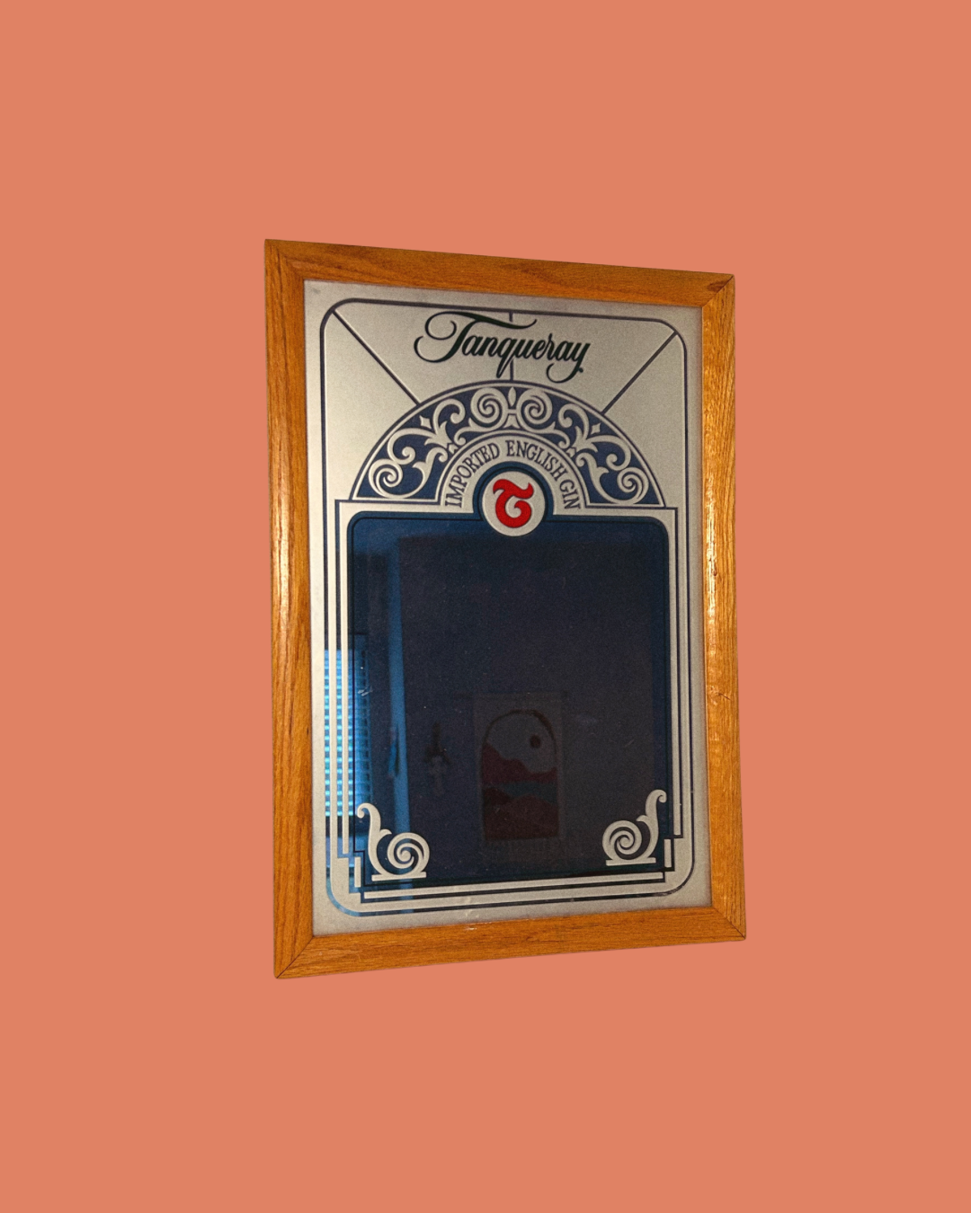 A vintage Tanqueray branded mirror with a decorative wooden frame