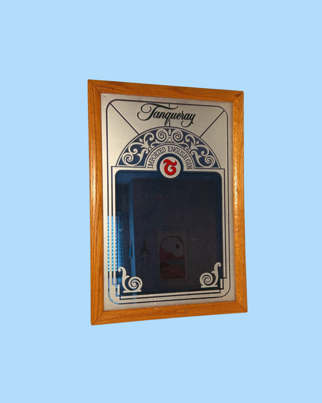 A vintage Tanqueray branded mirror with a decorative wooden frame