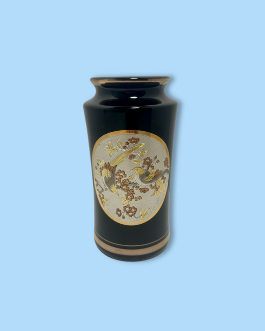 Black vase with gold and beige floral design on a light blue background