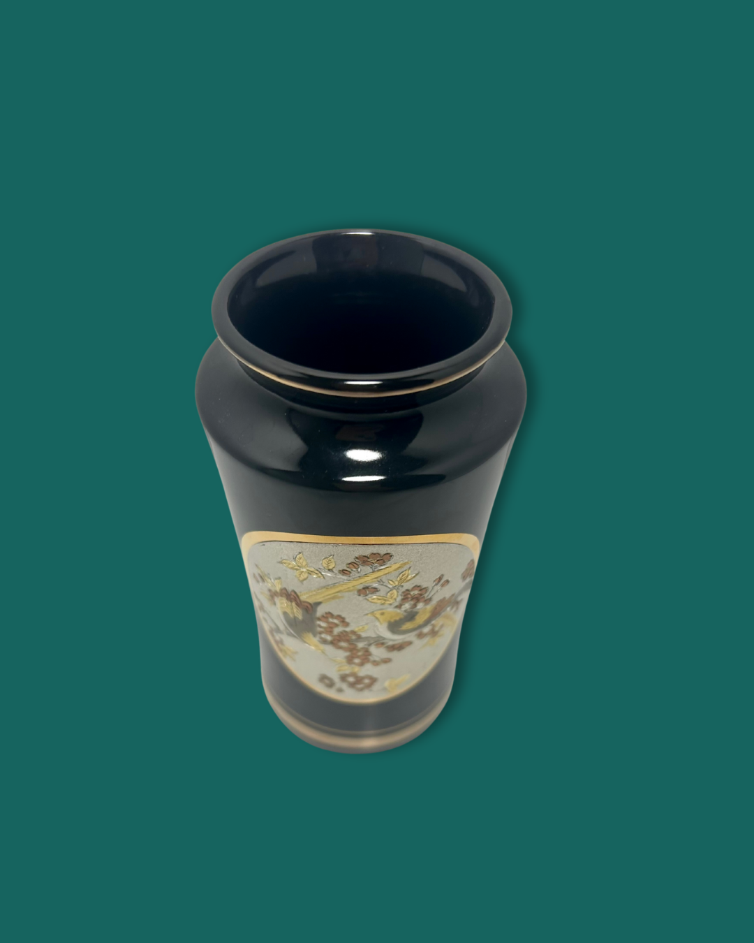 Black vase with decorative elements on a green background