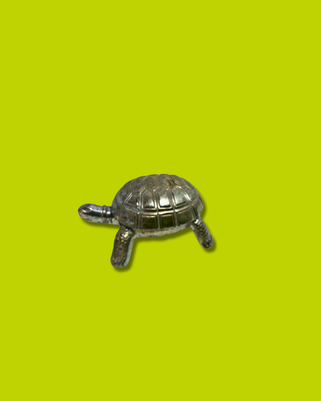 Small turtle figurine on a bright yellow background