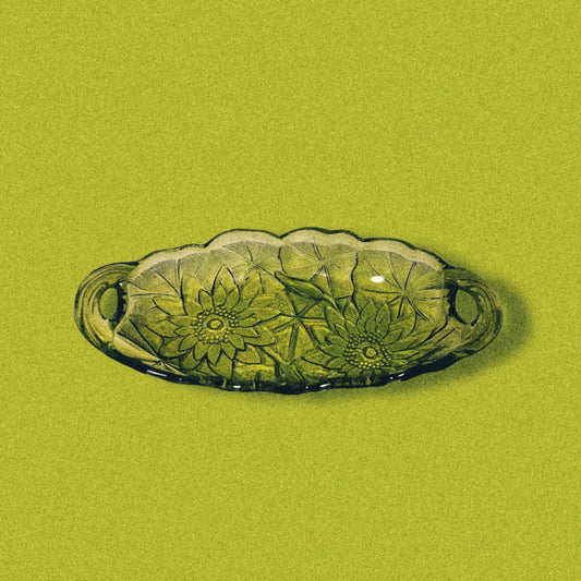 Avocado green glass candy dish with a sunflower pattern on a green background.