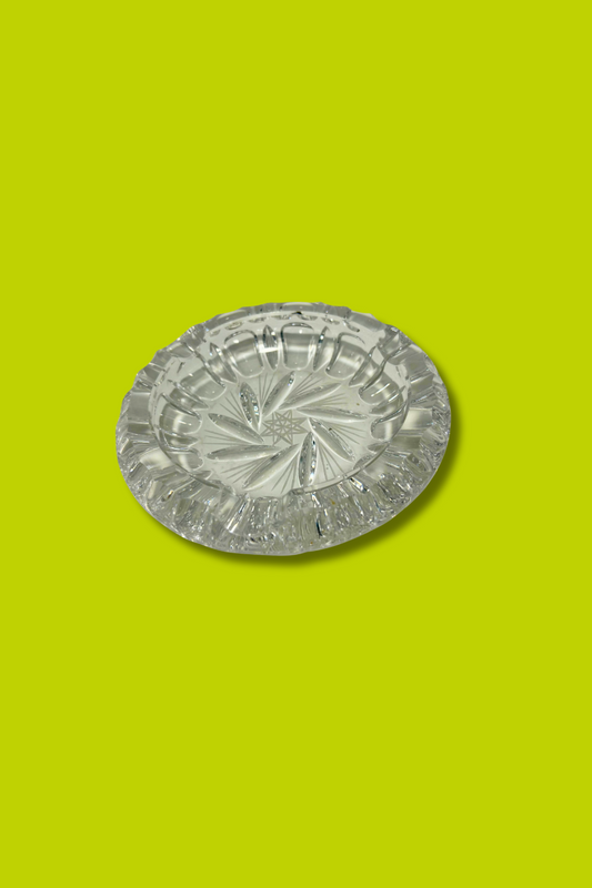 Clear crystal ashtray with Hob Star and pinwheel pattern on a green background