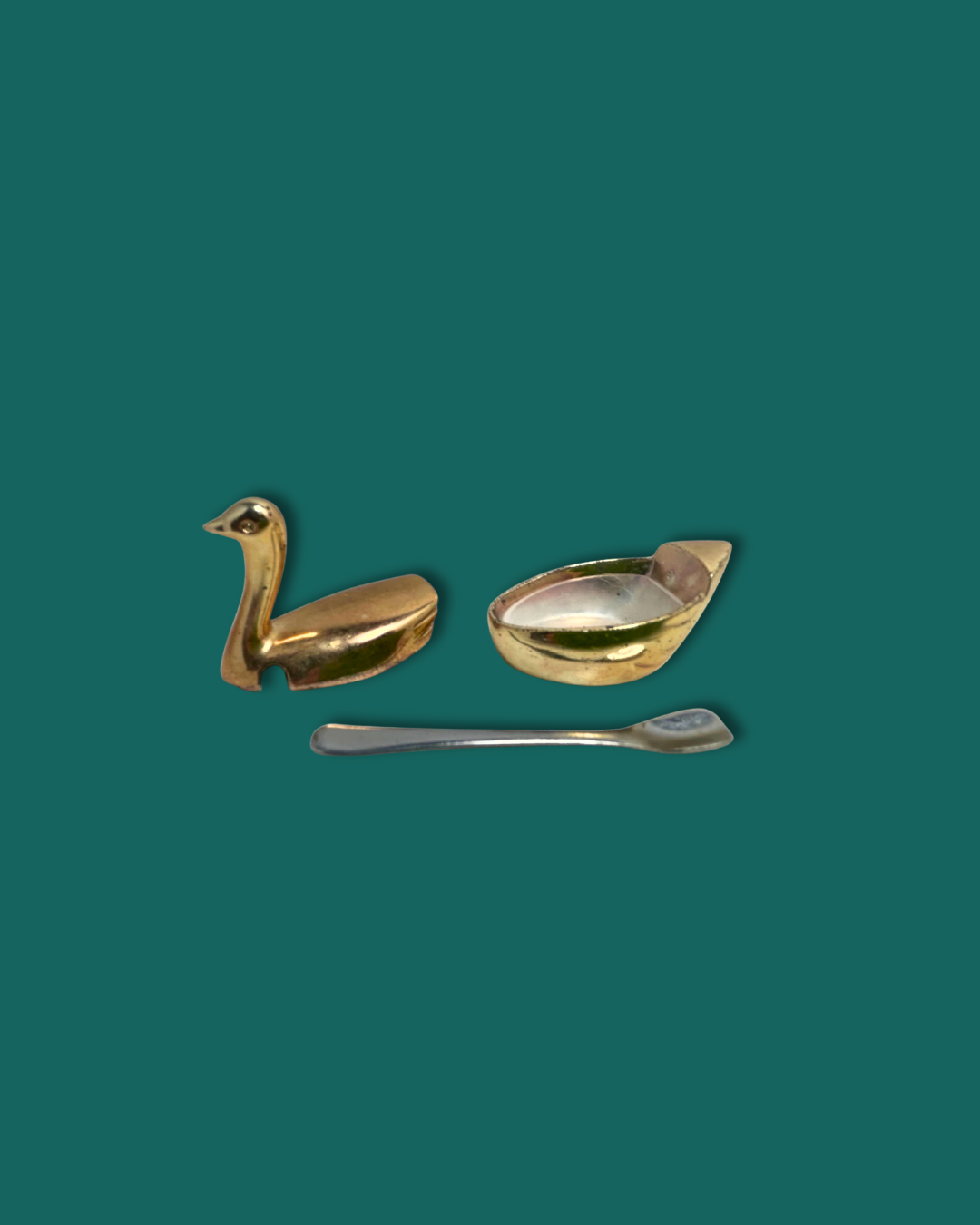 Gold swan-shaped spoon rest and silver spoon on a green background